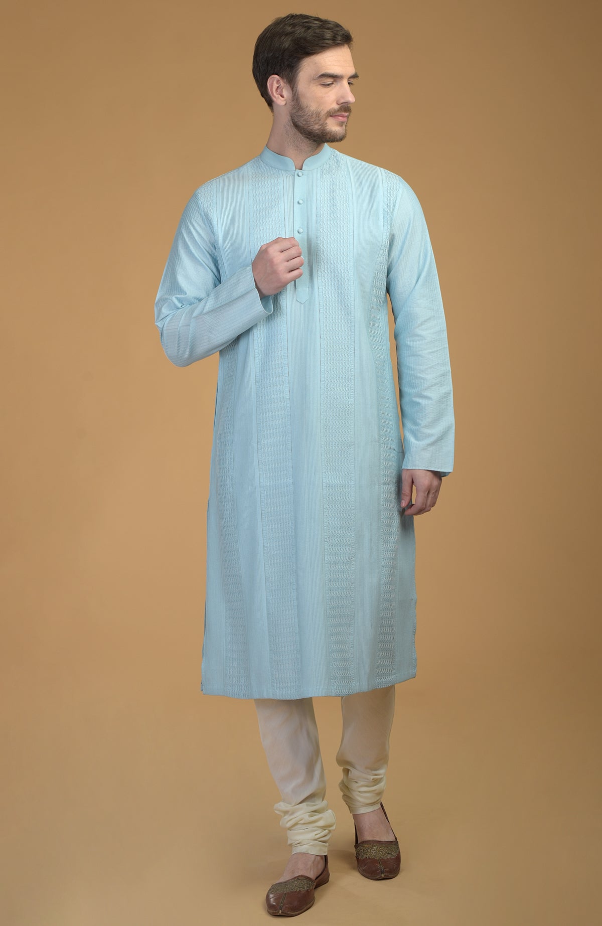 Ice blue kurta with pintuck and kantha detail, paired with ivory churidar and brown juttis.