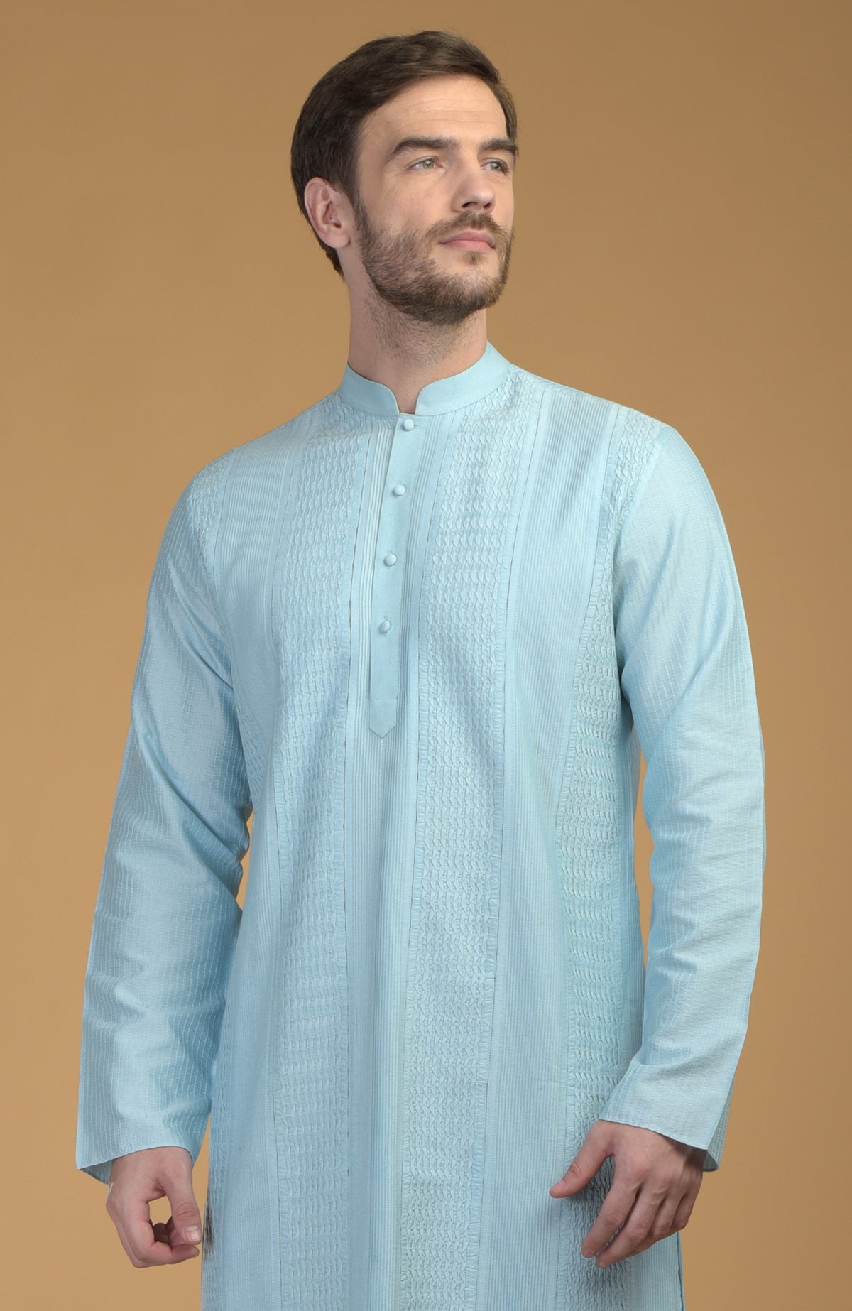 An ice blue kurta with pintuck and kantha details, worn by a man.