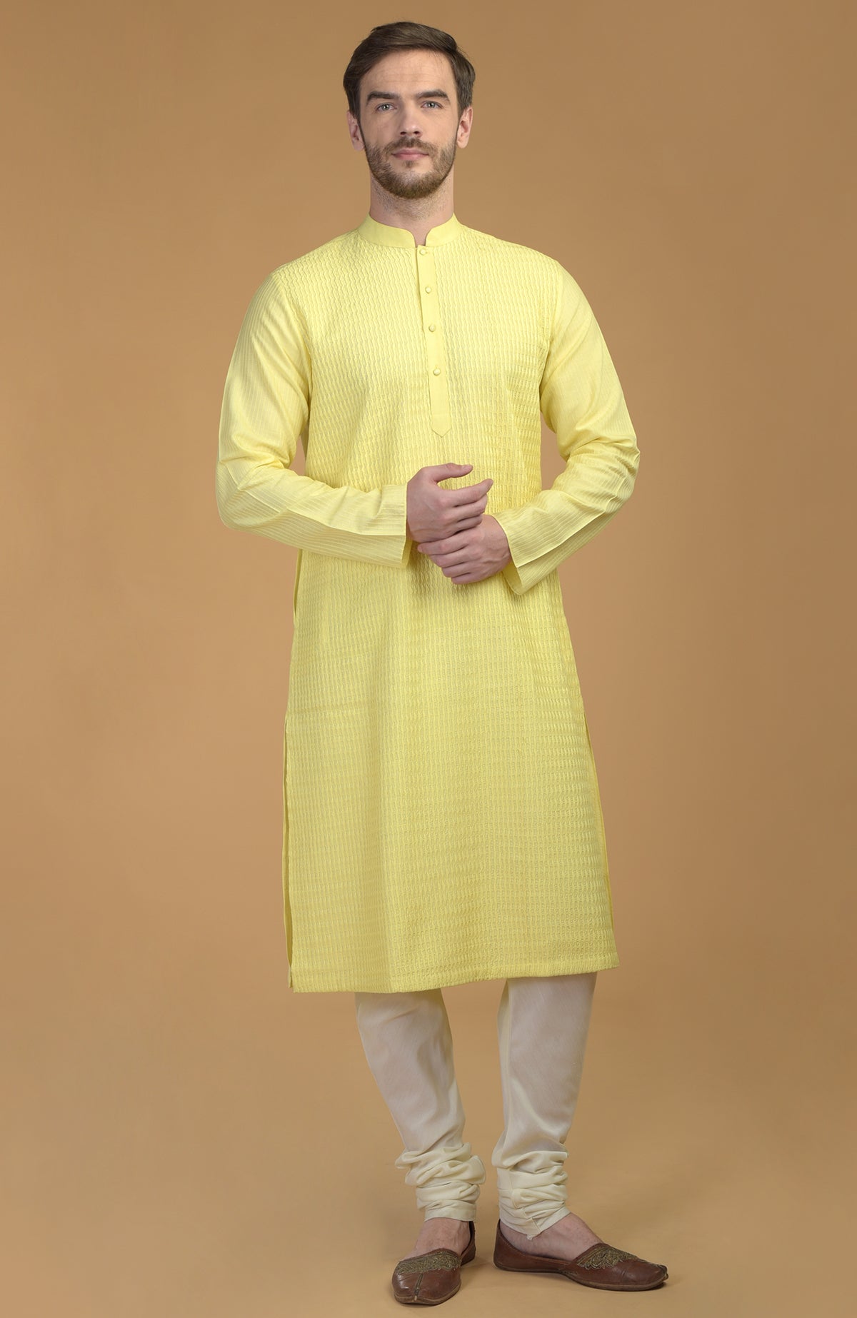 A man models a lemon yellow kurta with pintuck and kantha details and ivory churidars.