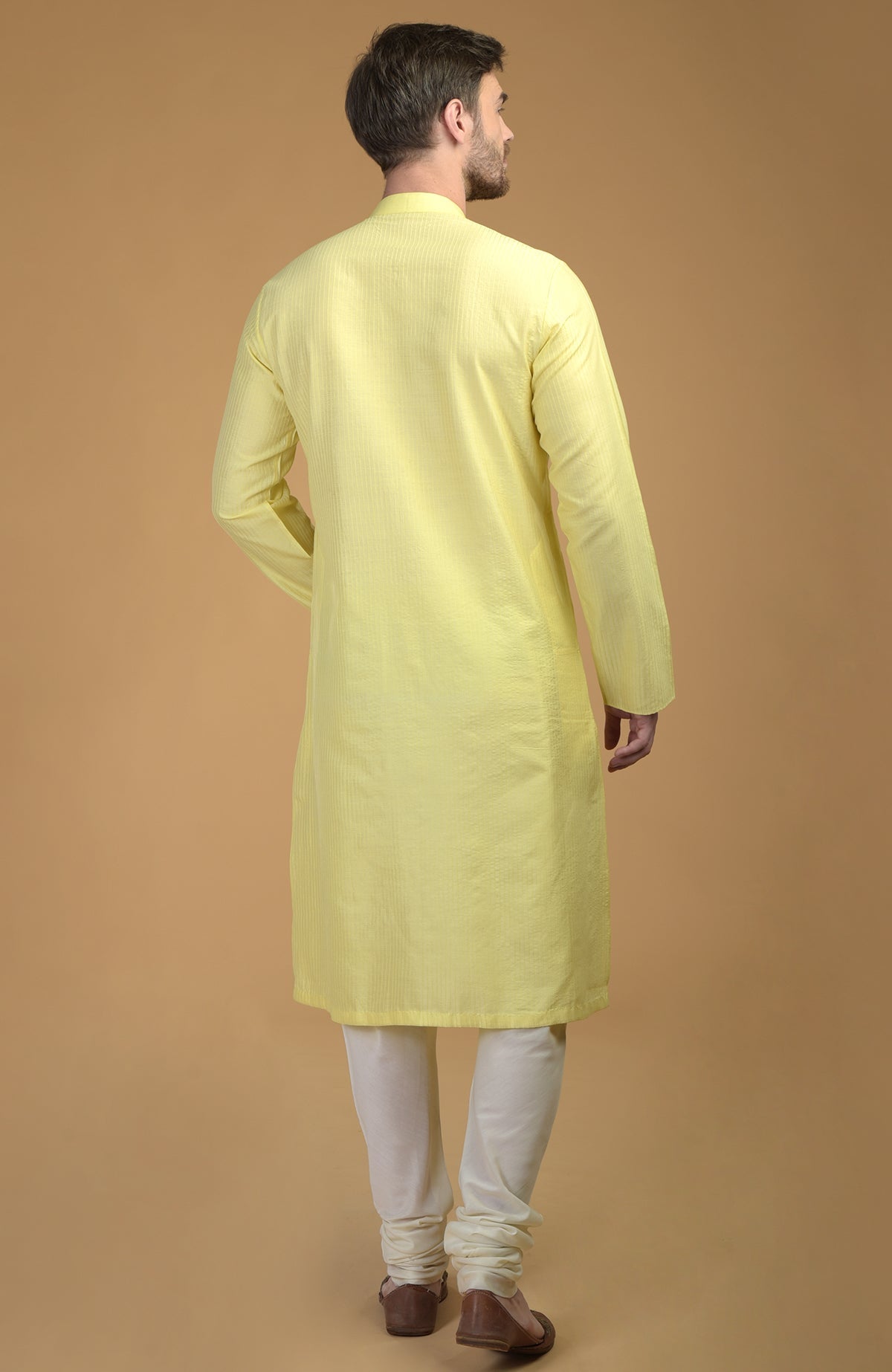 A man from behind wearing a lemon yellow kurta with pintuck and kantha detail.