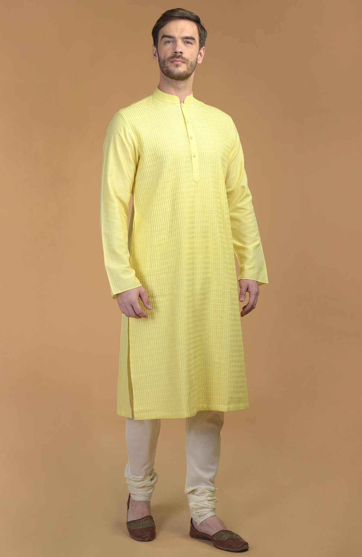 A man models a lemon yellow kurta with pintuck and kantha details and ivory churidars.