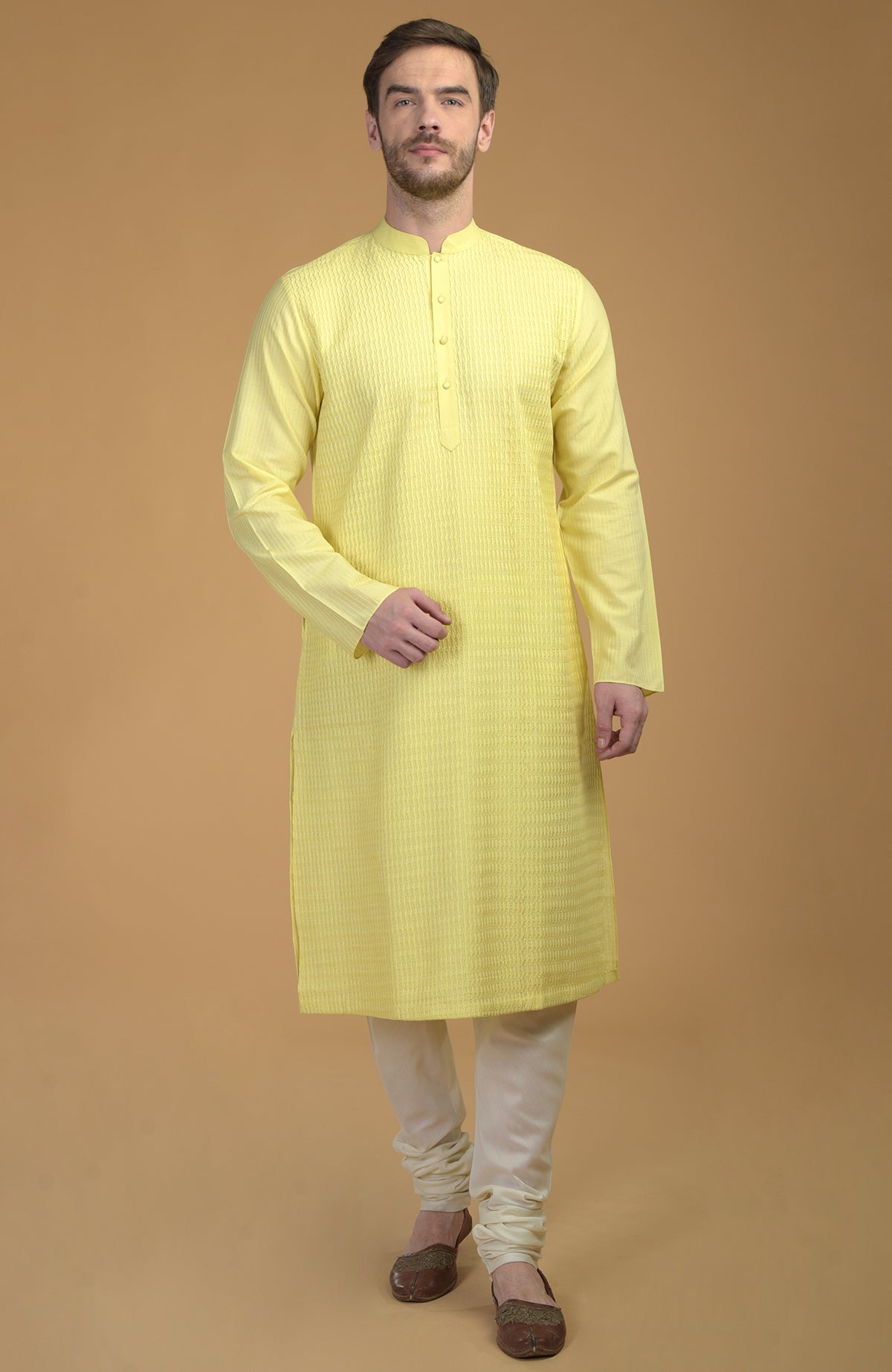 A man models a lemon yellow kurta with pintuck and kantha details and ivory churidars.