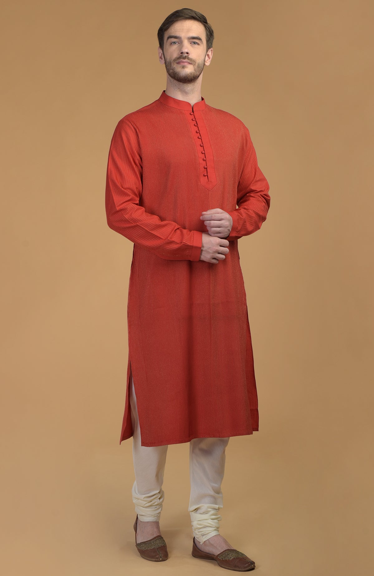 A man models a red kurta with pintuck and kantha details and ivory churidar.