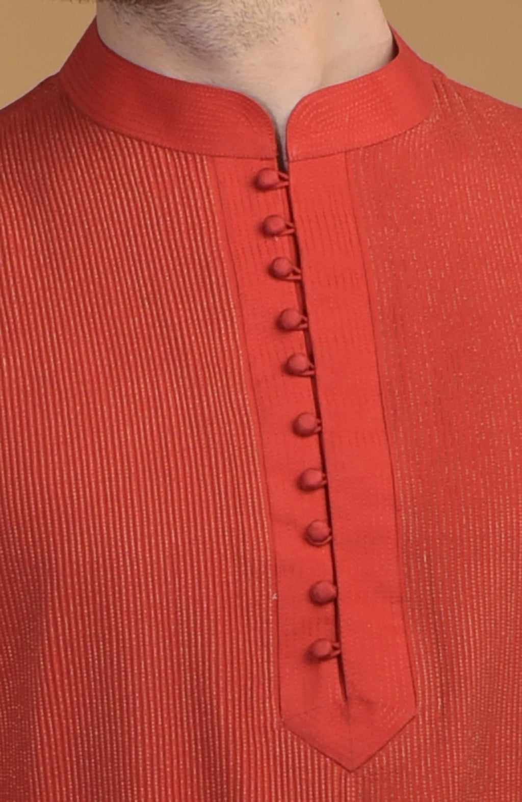 A close-up of a red kurta with pintuck and kantha details, featuring a buttoned placket.