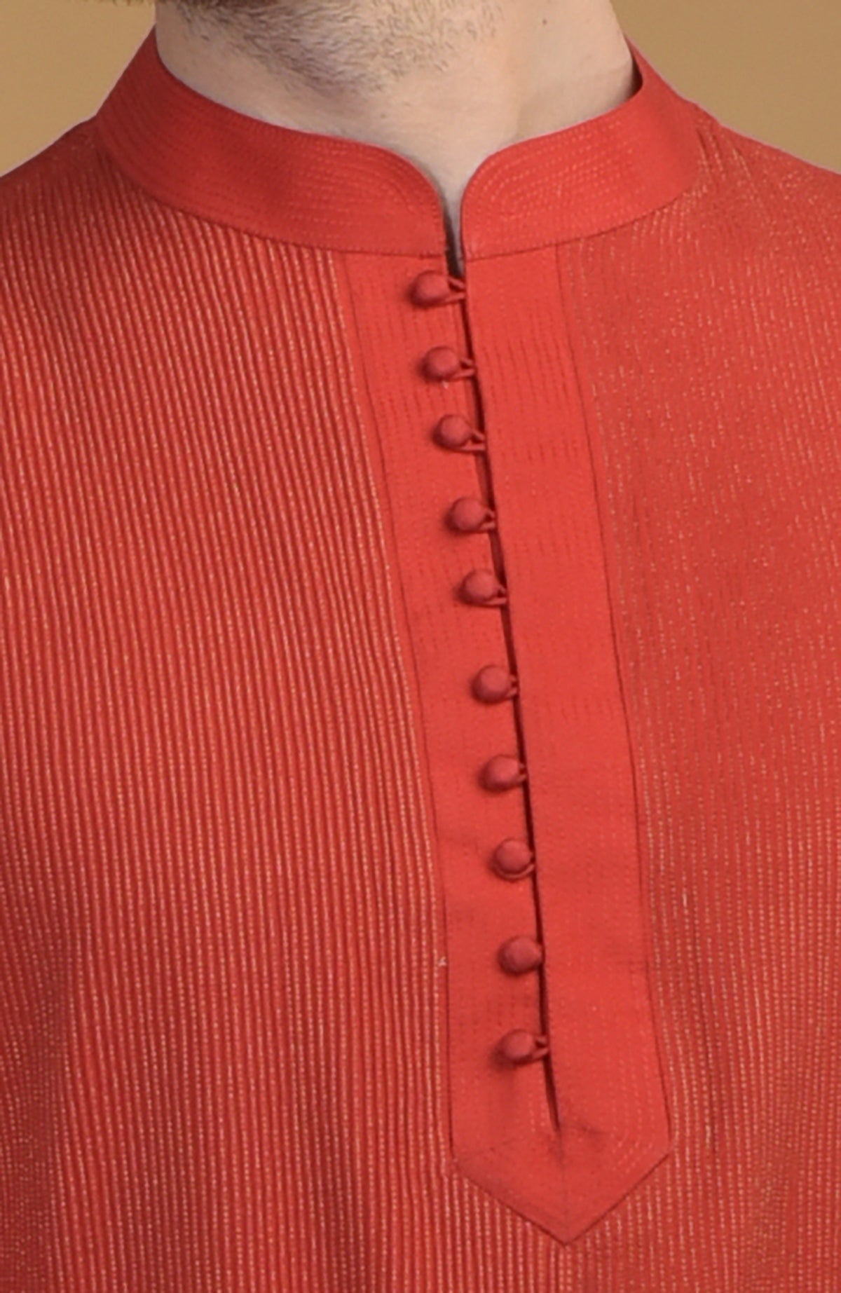 A close-up of a red kurta with pintuck and kantha details, featuring a buttoned placket.