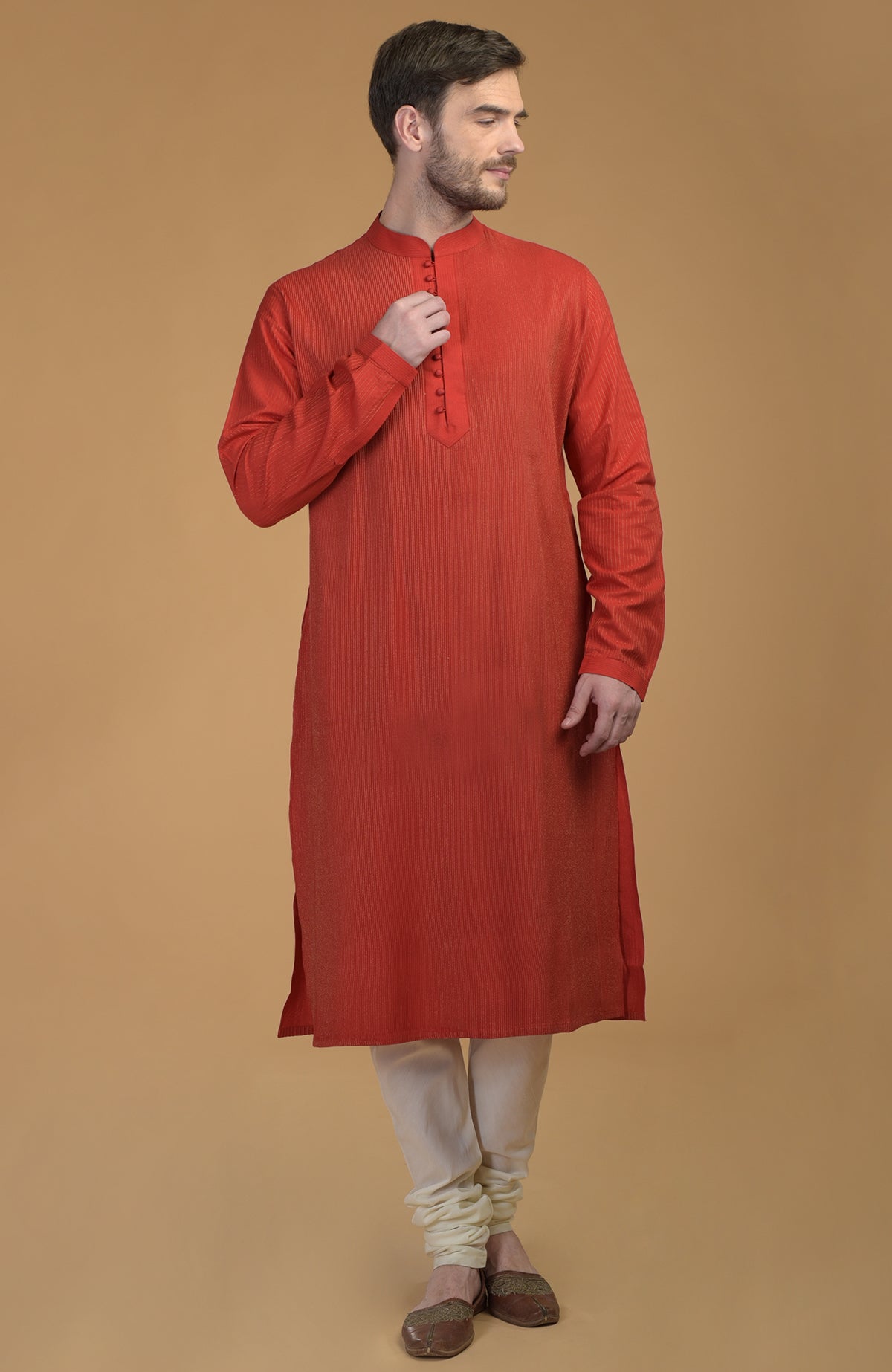 A man models a sienna kurta with pintuck and kantha details, and ivory churidar.