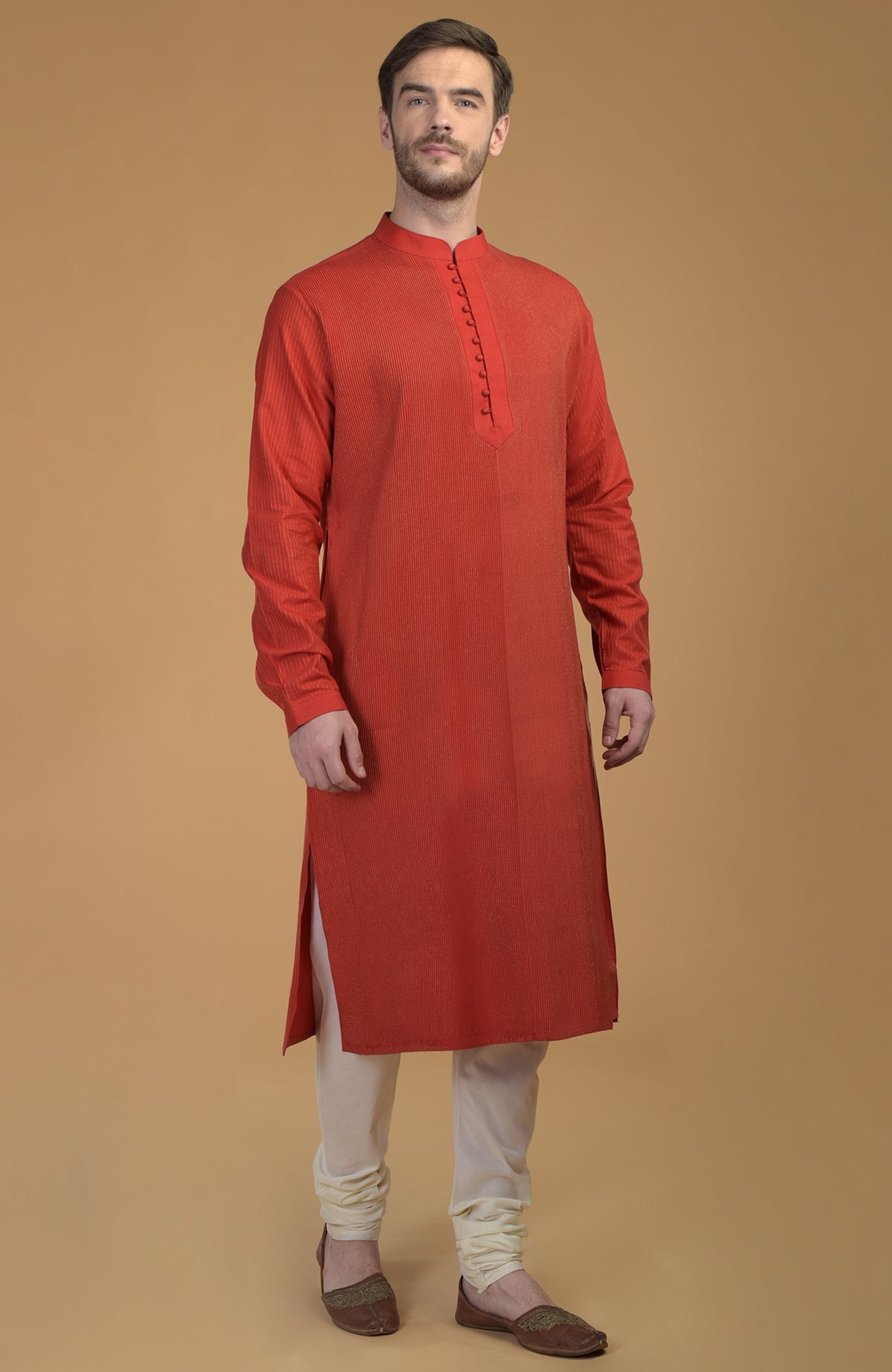 A man models a red Seinna Kurta with pintuck and Kantha details, paired with ivory churidars.