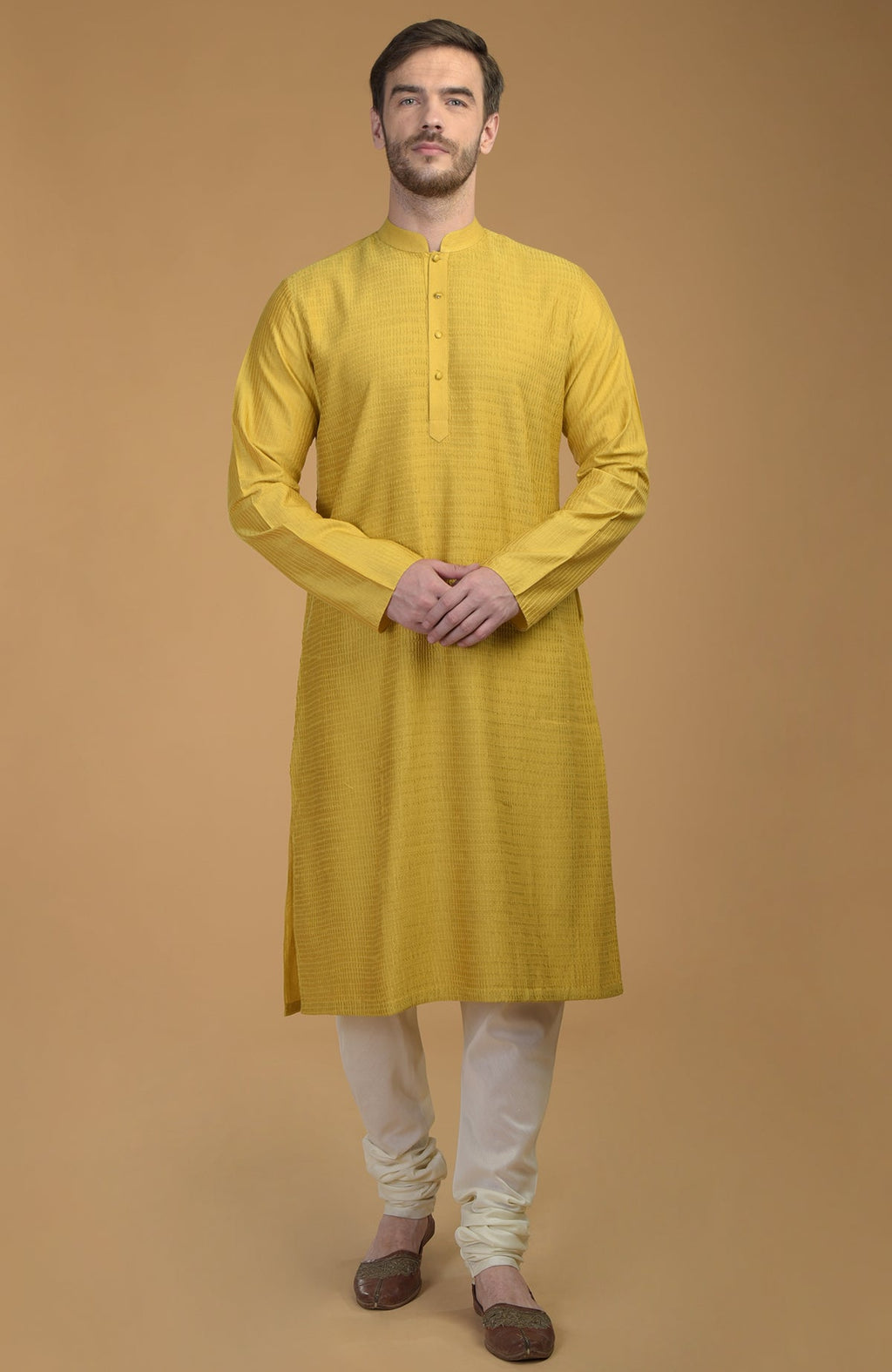 A man models a sunglow yellow kurta with pintuck and kantha detail and ivory churidars.