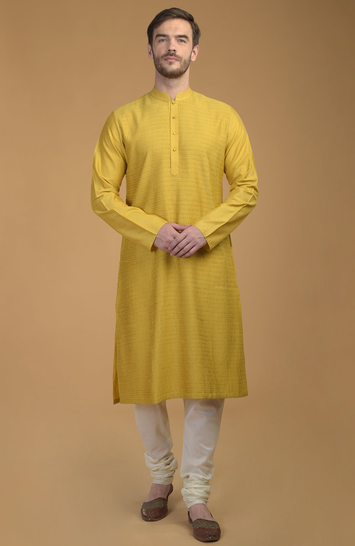 A man models a sunglow yellow kurta with pintuck and kantha detail and ivory churidars.