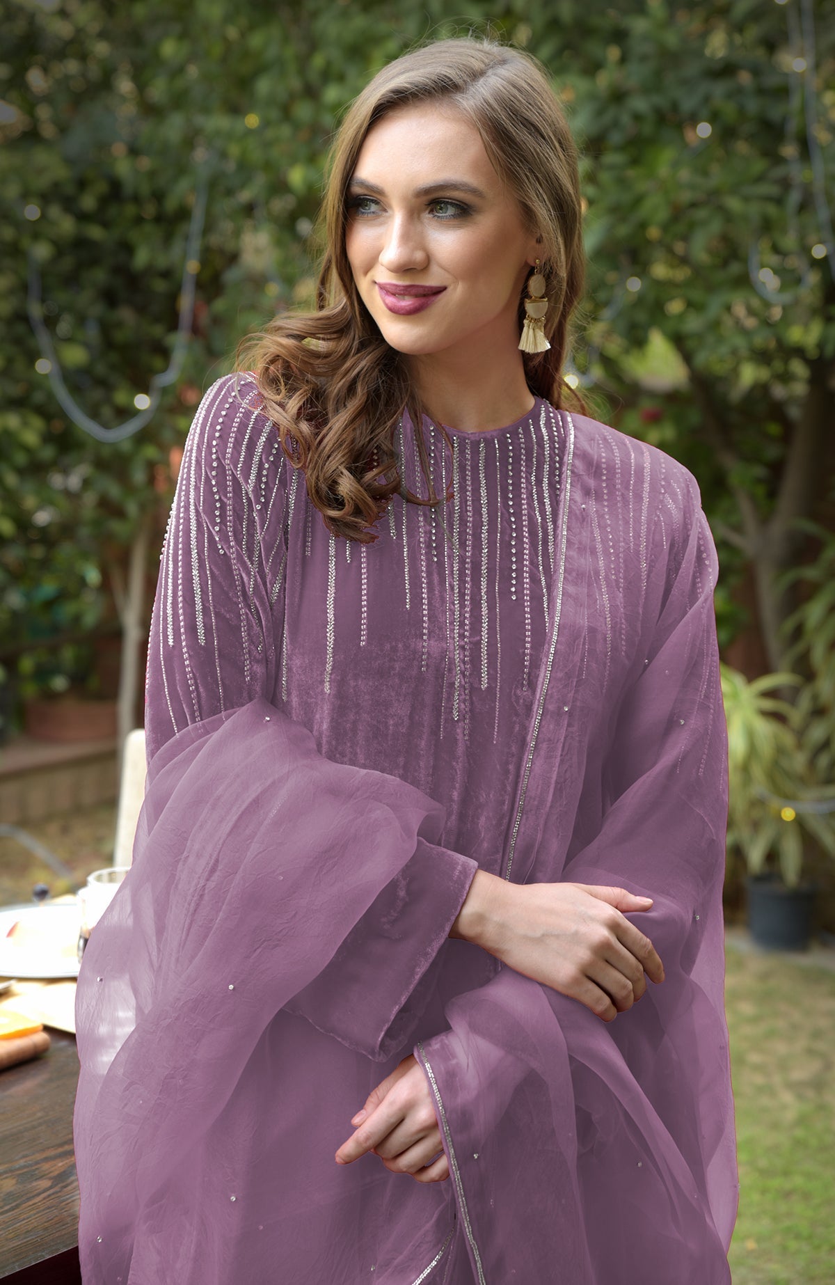 A woman in a purple velvet kurta with silver embroidery and a sheer dupatta.