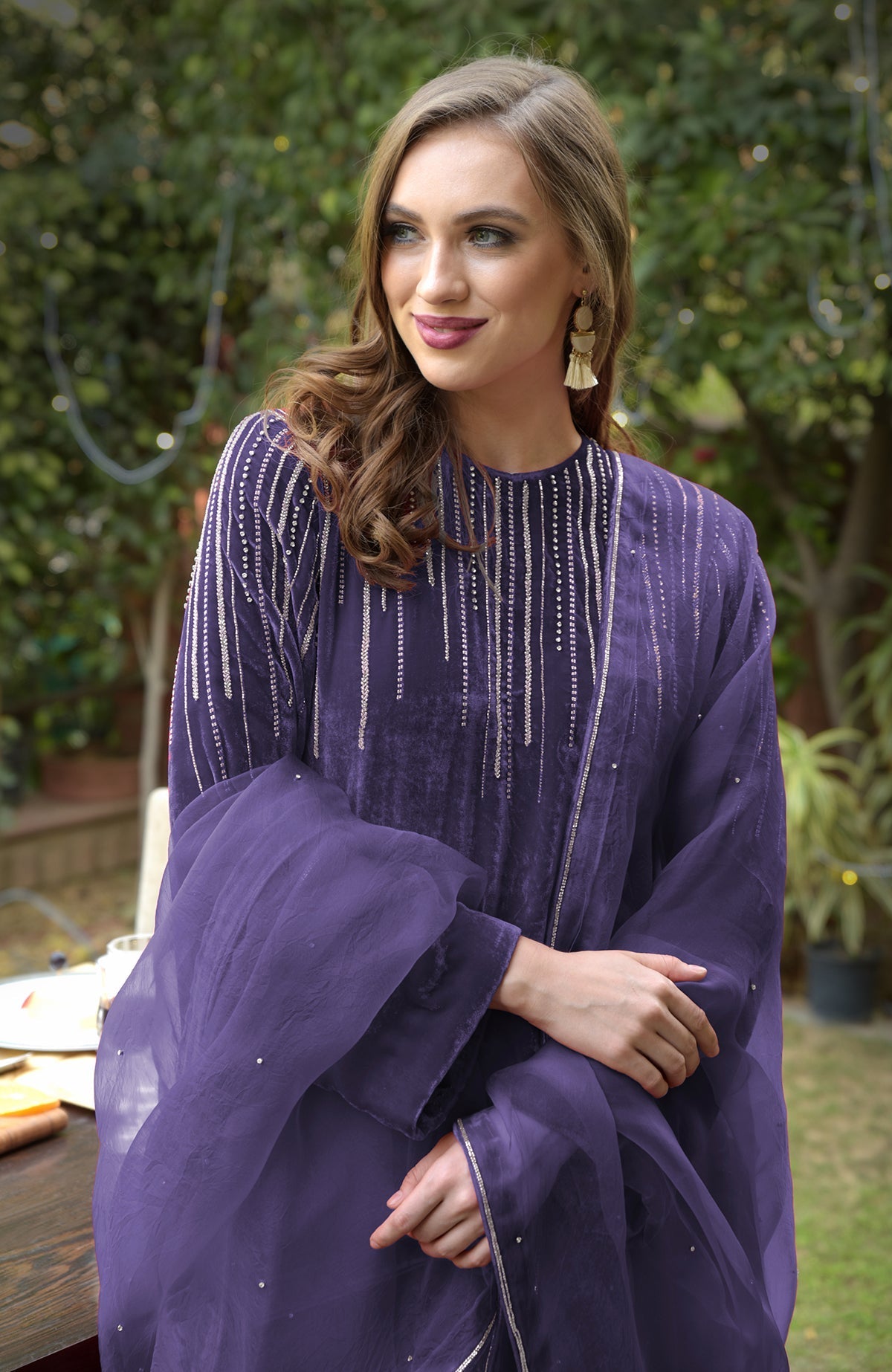 A woman in a purple velvet kurta with silver embroidery and a sheer dupatta.