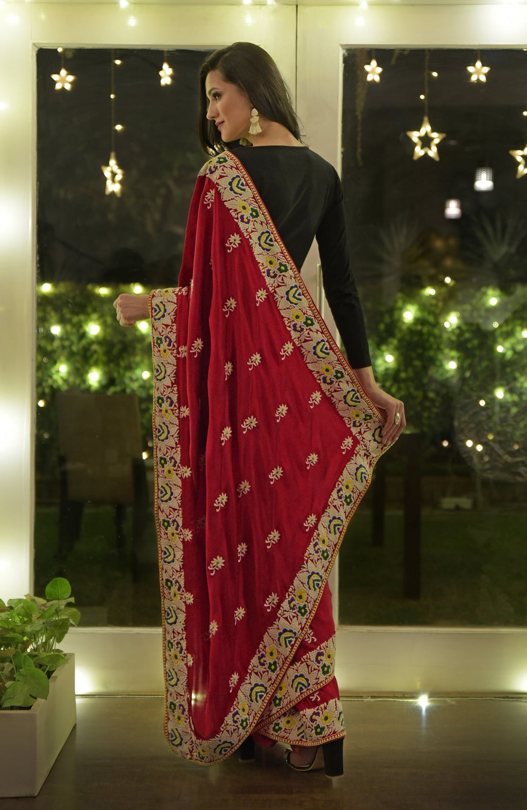 A woman models a red Parsi Gara hand-embroidered saree with a black blouse.