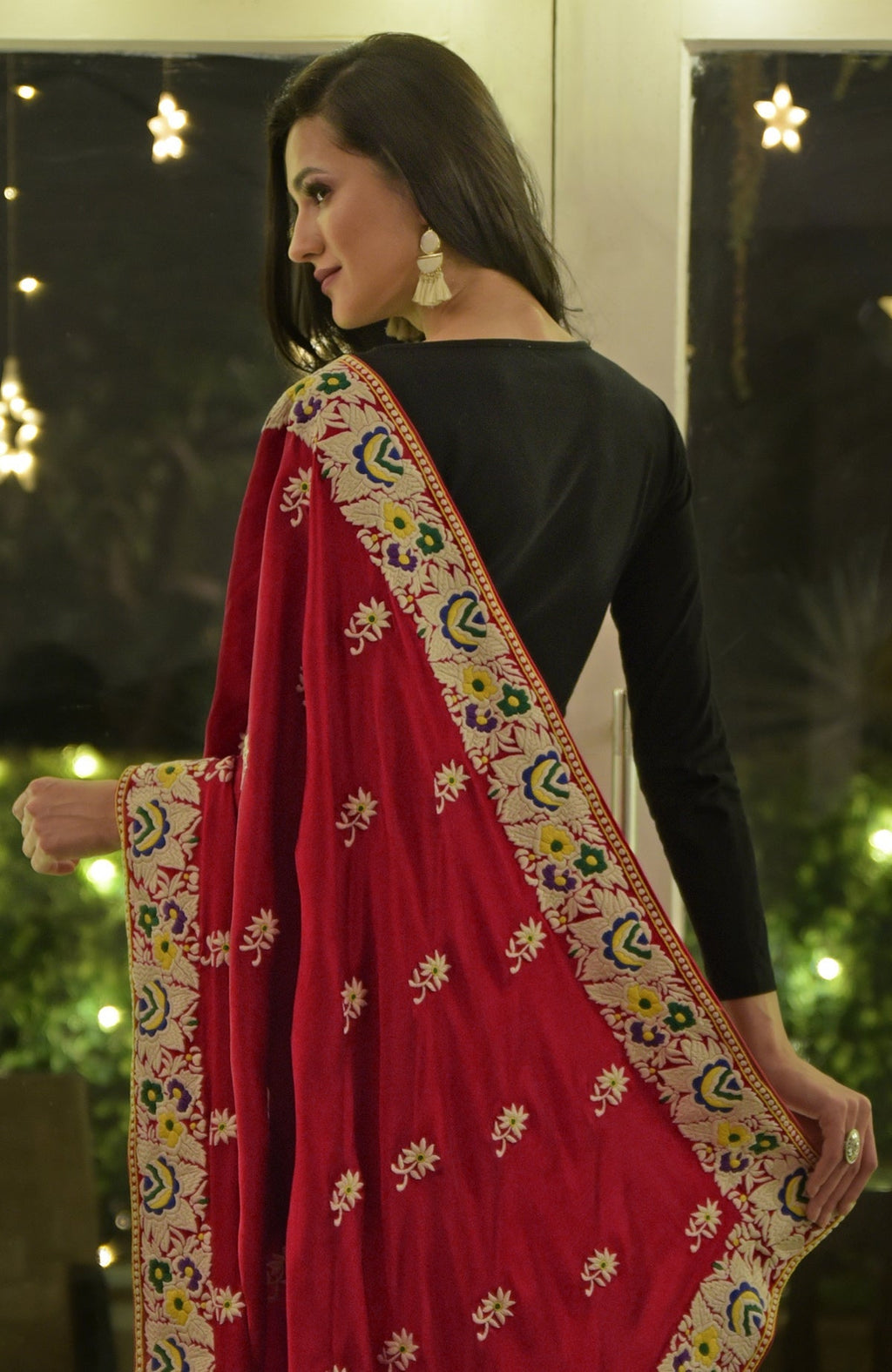A woman models a red Parsi Gara hand-embroidered saree with a black top.
