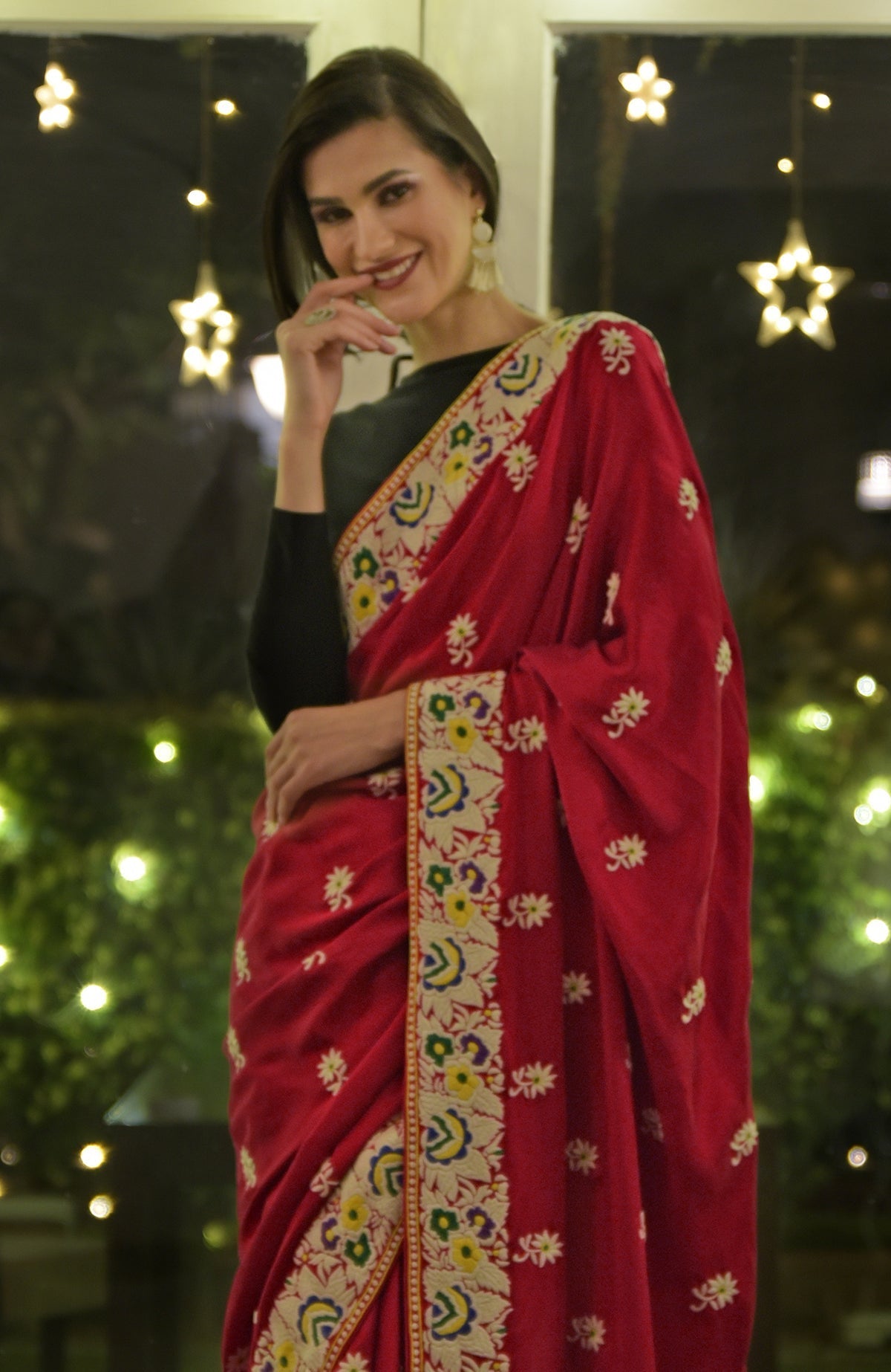 A woman models a red Parsi Gara hand-embroidered saree with floral patterns.