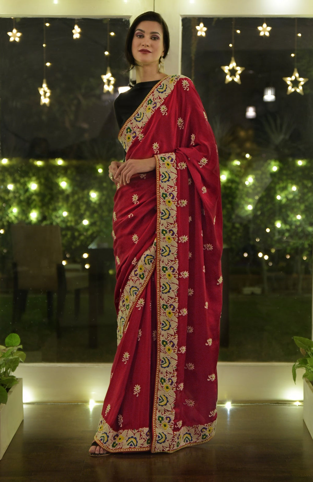 A woman models a red Parsi Gara hand-embroidered saree with floral patterns.