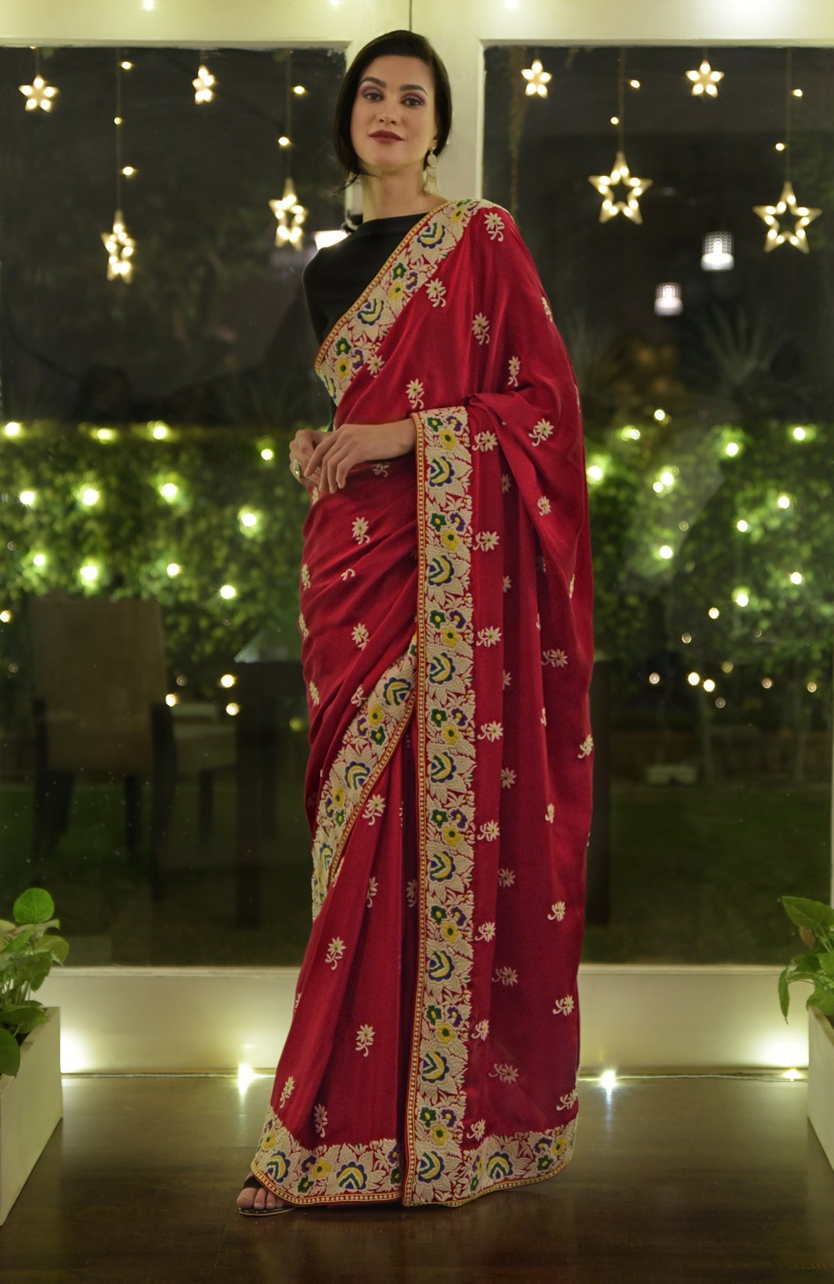 A woman models a red Parsi Gara hand-embroidered saree with floral patterns.