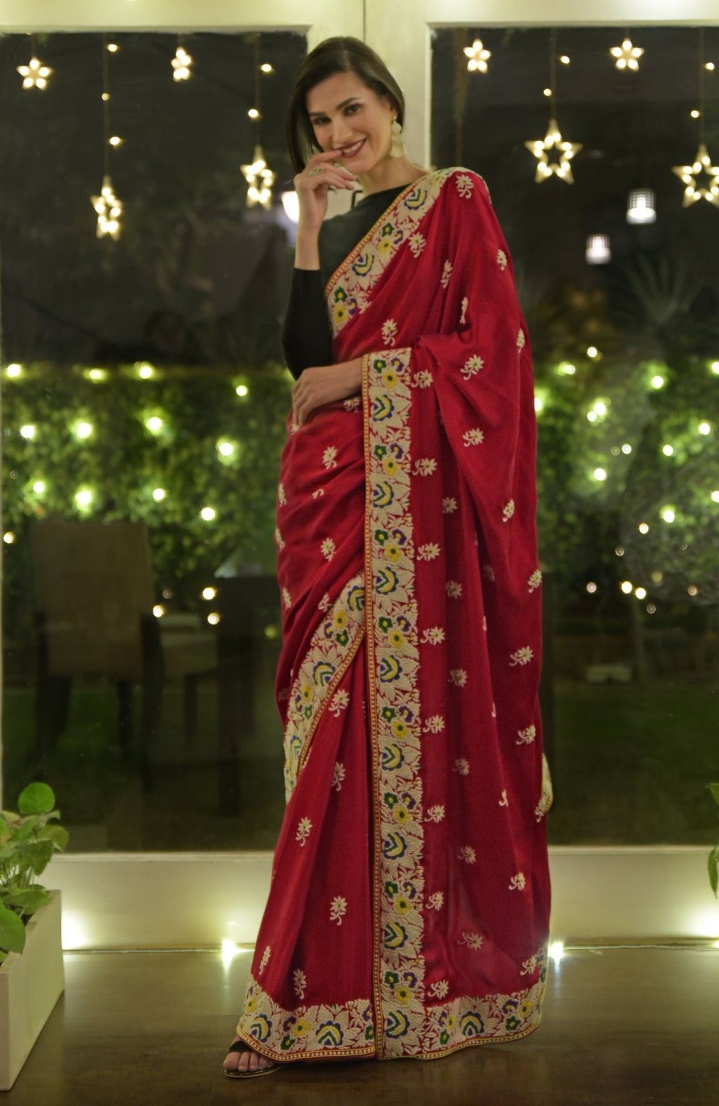A woman models a red Parsi Gara hand-embroidered saree with floral patterns.