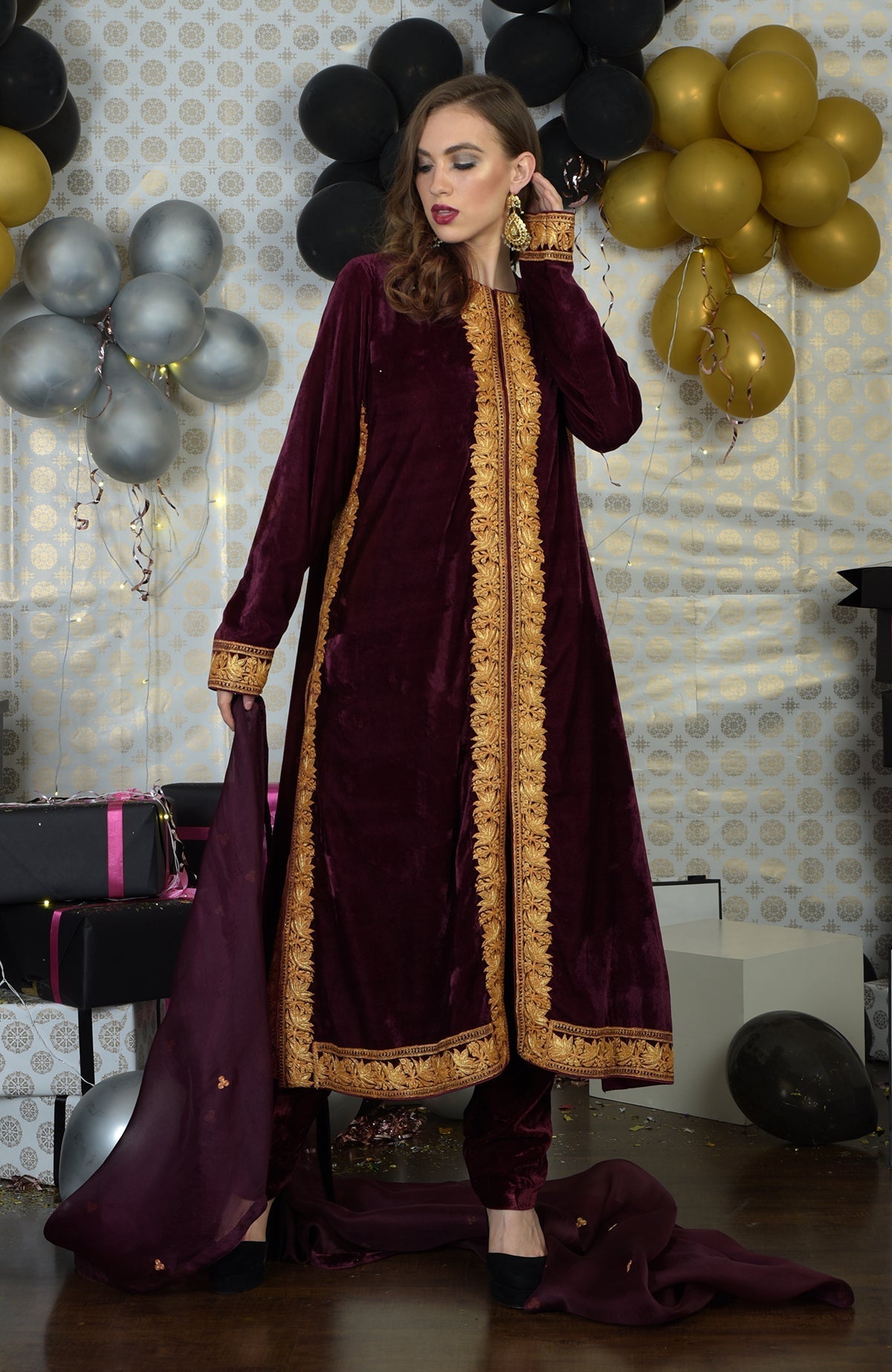 Burgundy velvet kurta set with gold Tilla embroidery and a matching dupatta.
