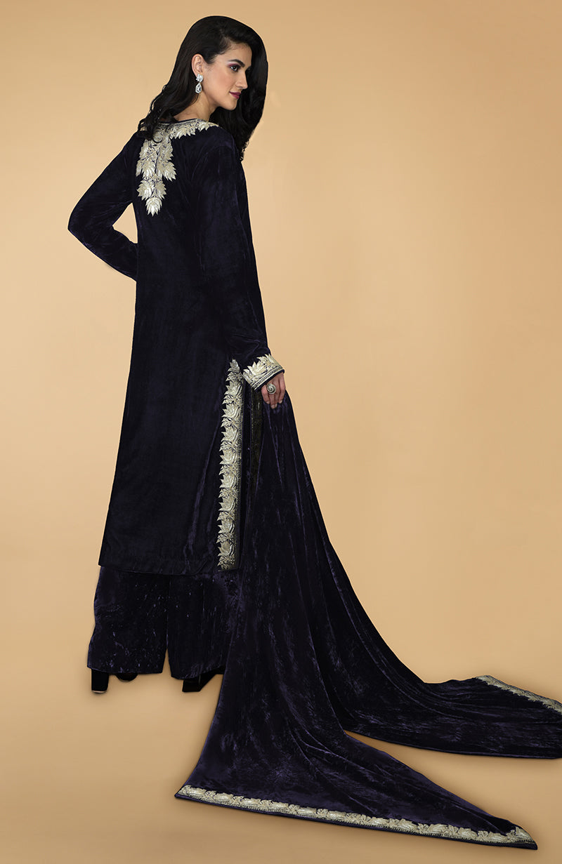 A woman models a midnight blue silk velvet kurta set with Kashmiri tilla embroidery.