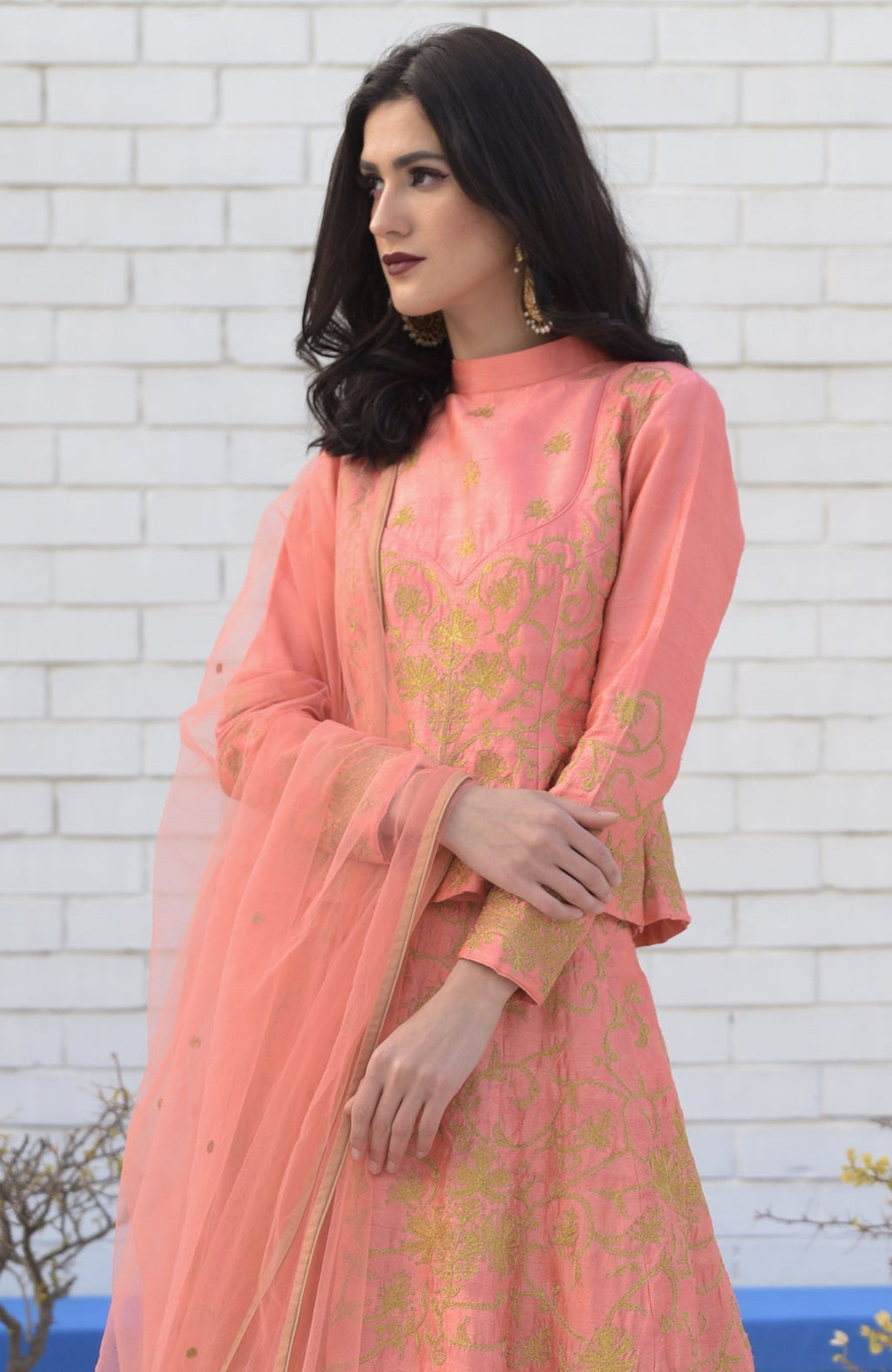 A woman models a peach echo Kashmiri chinar tilla embroidered lehenga set.