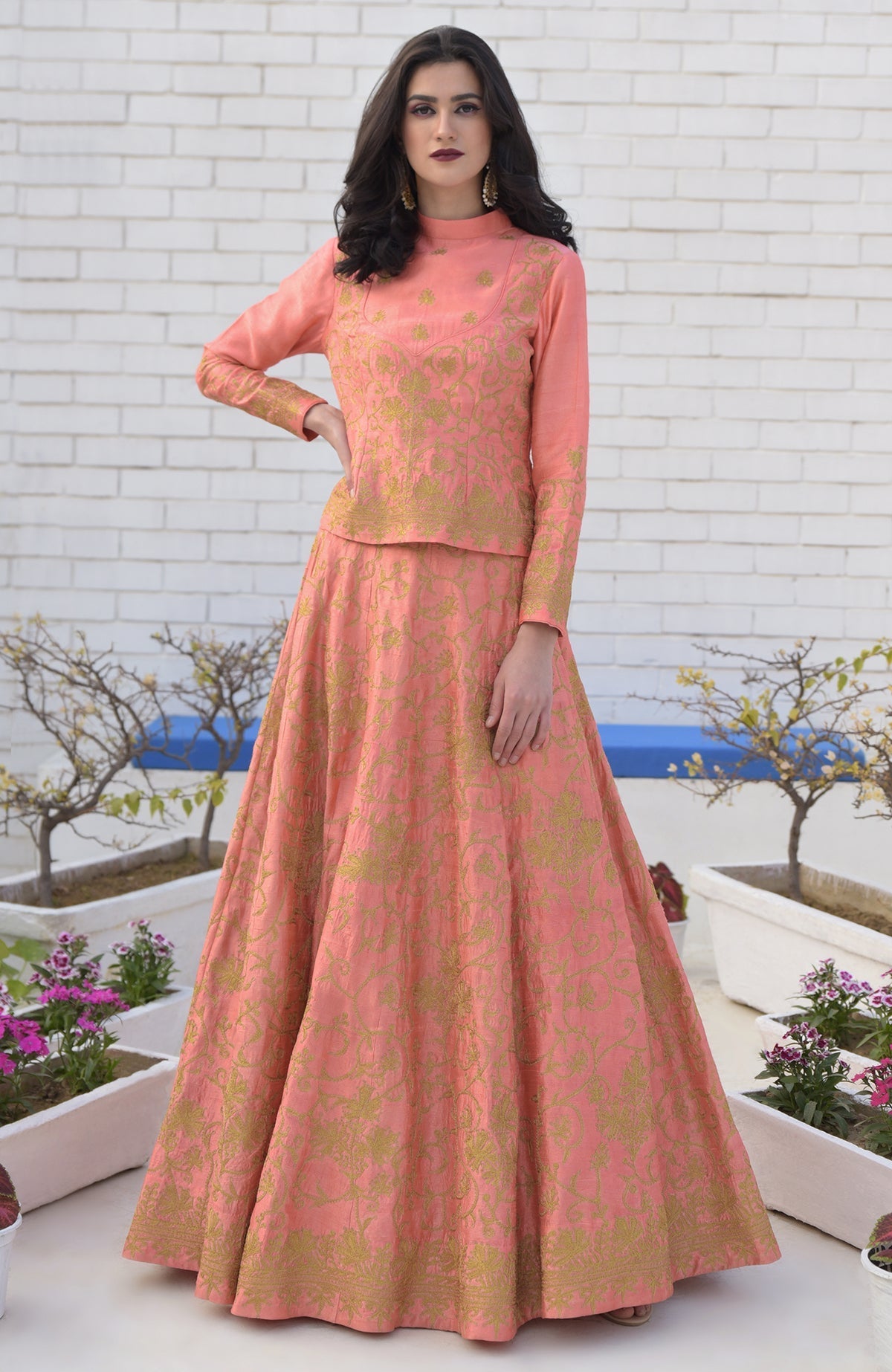 A woman models a peach lehenga set with gold Kashmiri tilla aari embroidery.