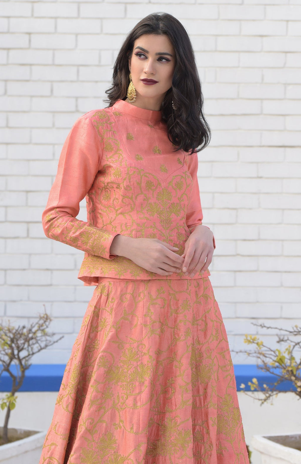 A woman models a peach echo Kashmiri tilla embroidered lehenga set.