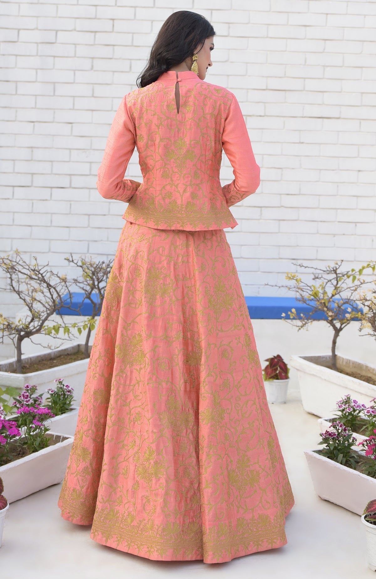 A woman models a peach echo Kashmiri chinar tilla embroidered lehenga set.