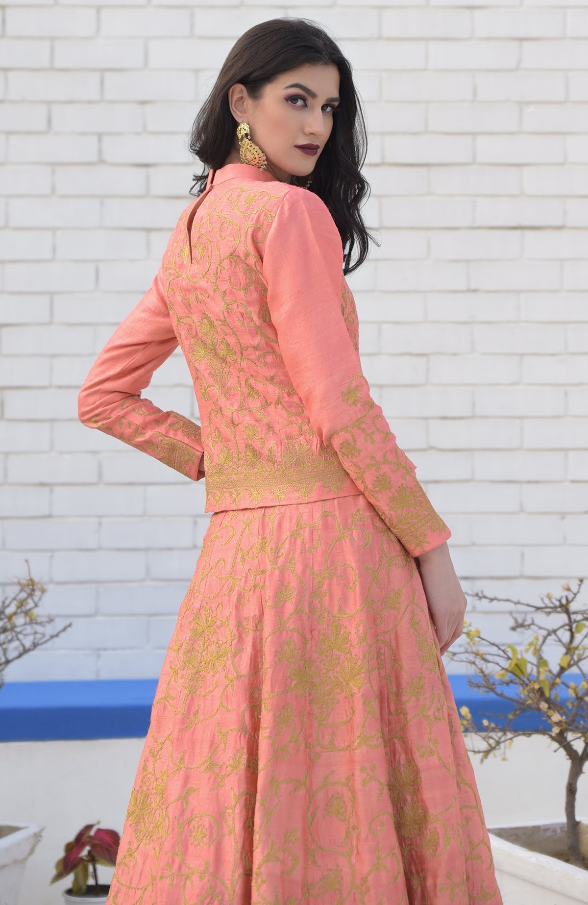 A woman models a peach echo Kashmiri chinar tilla embroidered lehenga set.