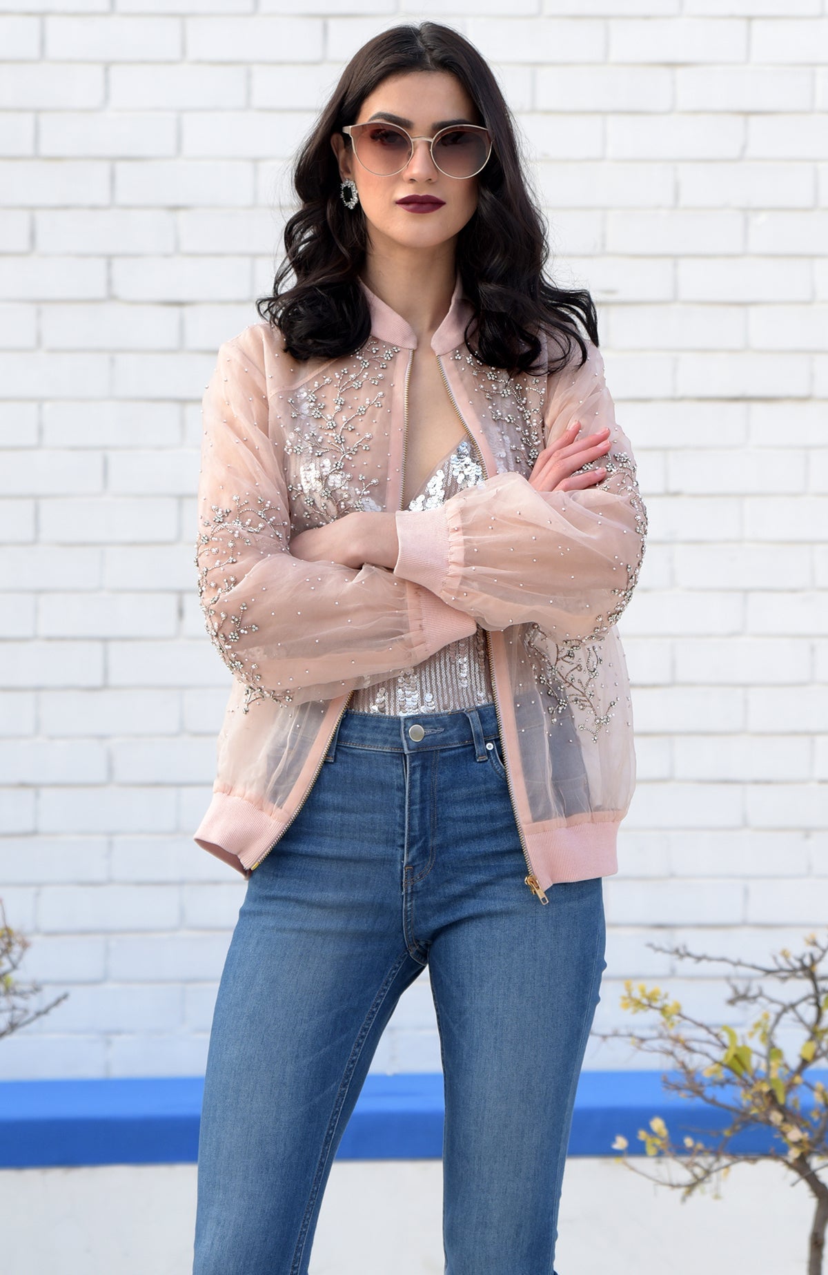 A woman models a peach organza bomber jacket with crystal floweret hand embroidery.