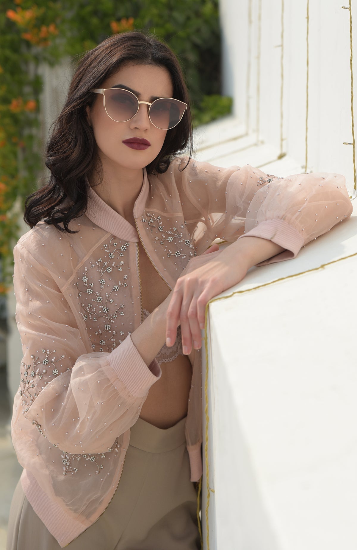 A woman models a peach organza bomber jacket with crystal floweret embroidery.