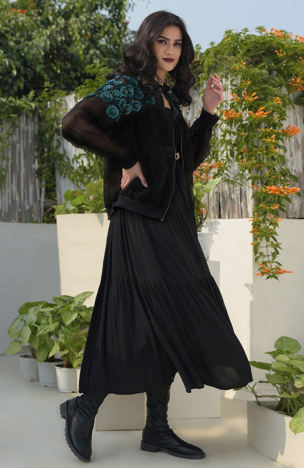 Black organza bomber jacket with blue 3D floral embroidery, worn over a black dress.