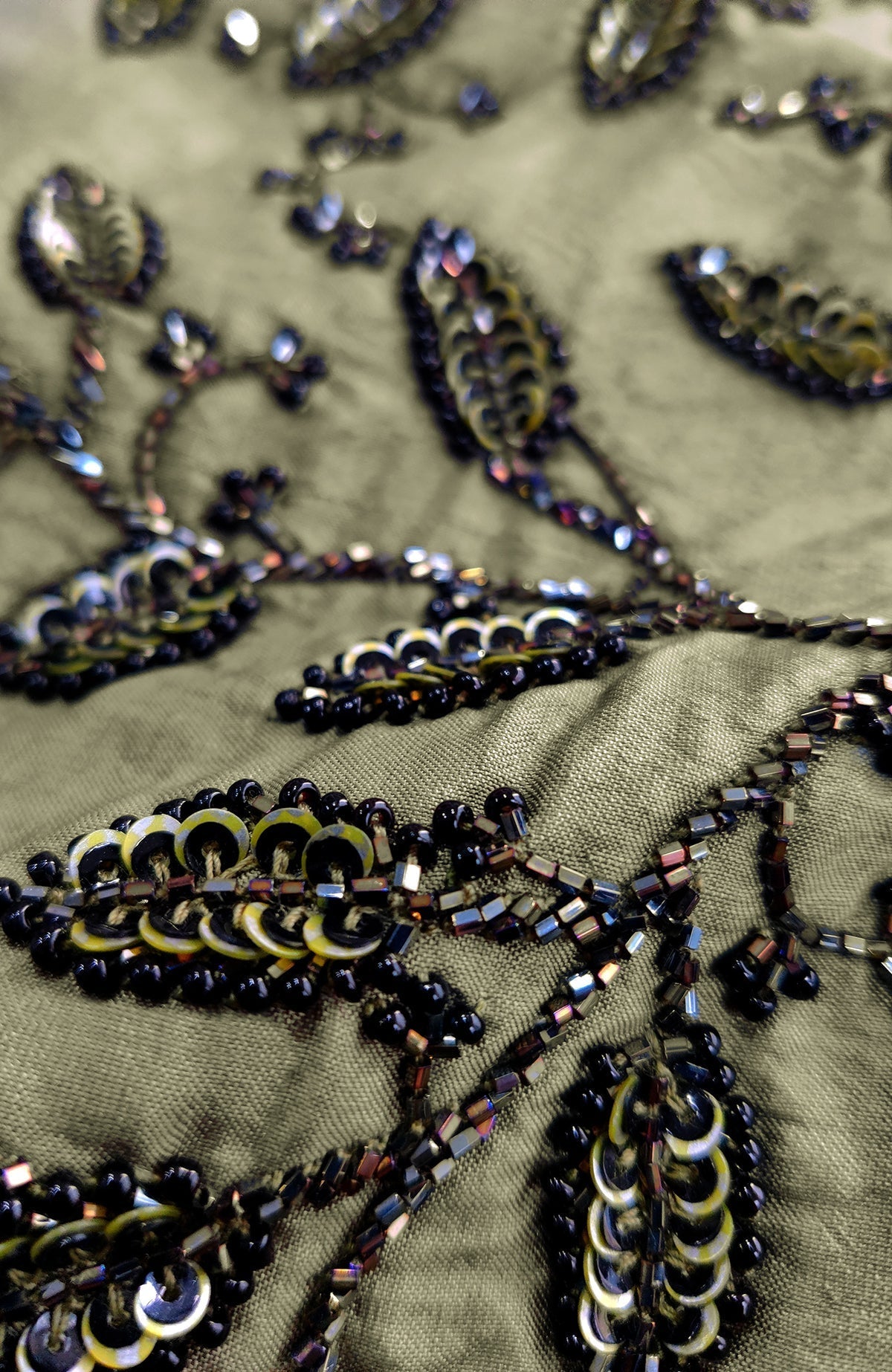 Olive green fabric with black and iridescent sequin and bead embroidery.