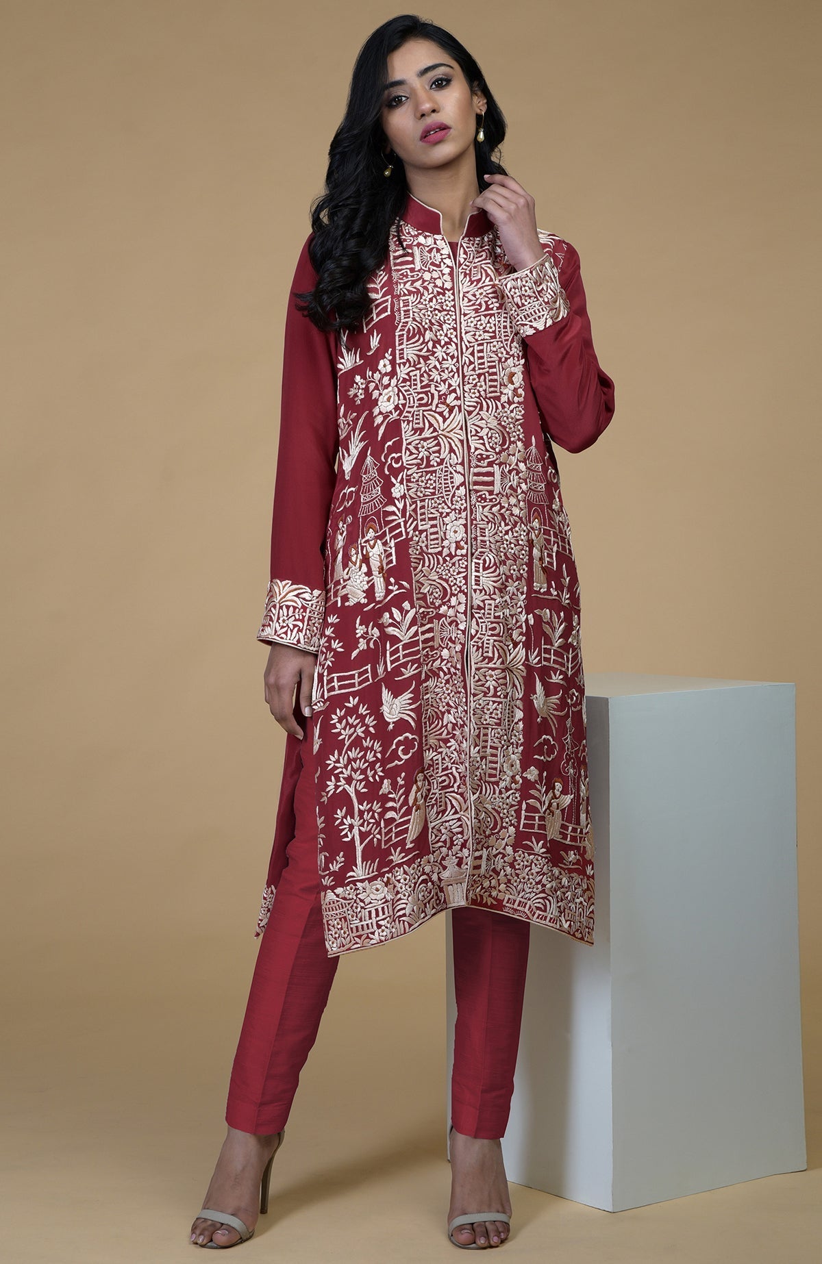 Shiraz red Parsi Gara embroidered jacket with beige, orange, and lilac Cheena Cheeni motifs and beige pants.