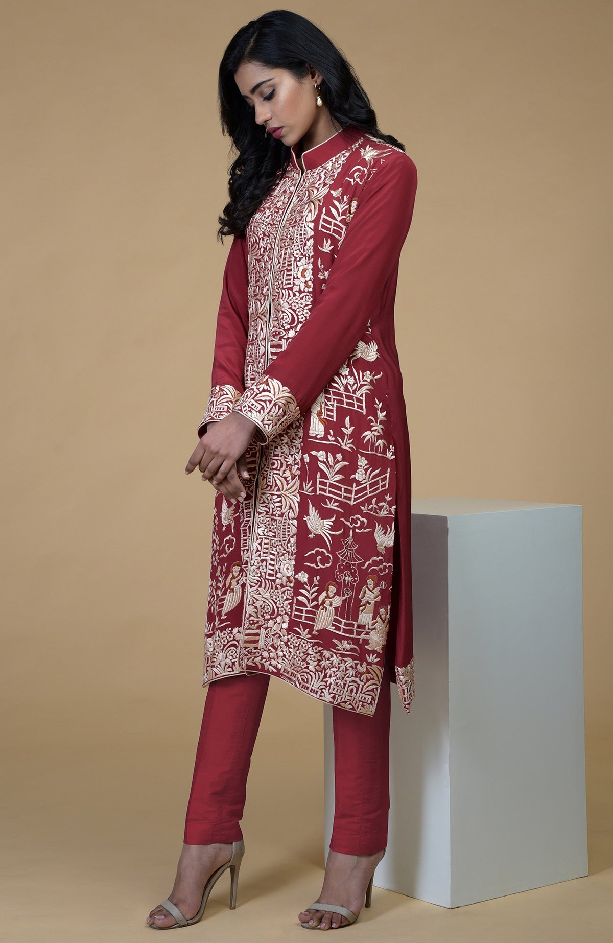 Shiraz red Parsi Gara embroidered jacket with beige, orange, and lilac Cheena Cheeni motifs and beige pants.