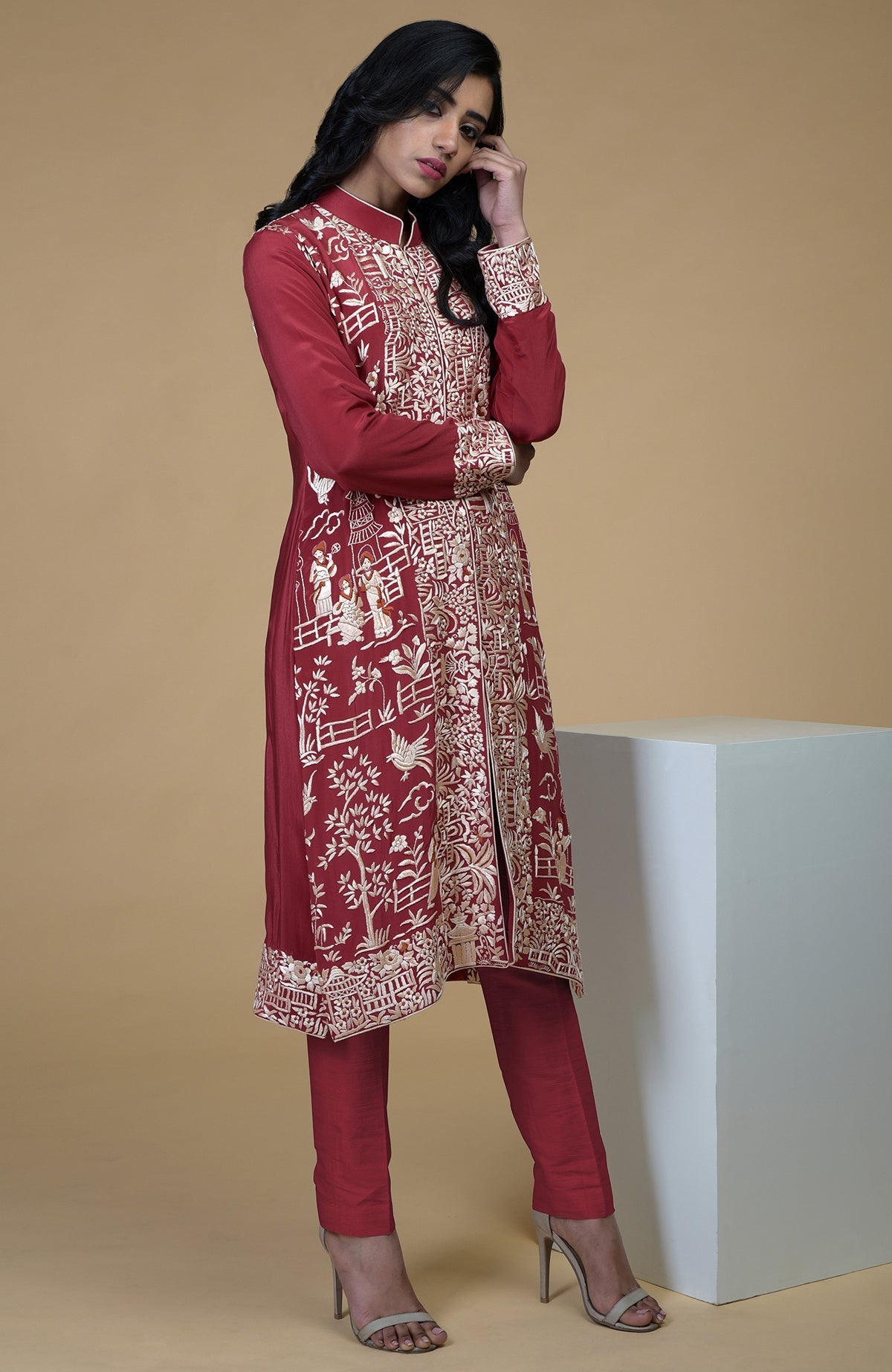 Shiraz red Parsi Gara embroidered jacket with beige, orange, and lilac Cheena Cheeni motifs and beige pants.