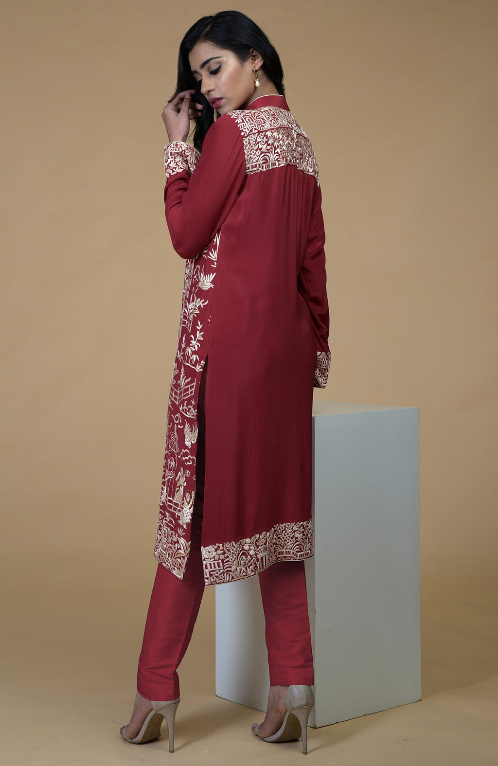 Shiraz red Parsi Gara embroidered jacket with beige, orange, and lilac Cheena Cheeni motifs and beige pants.