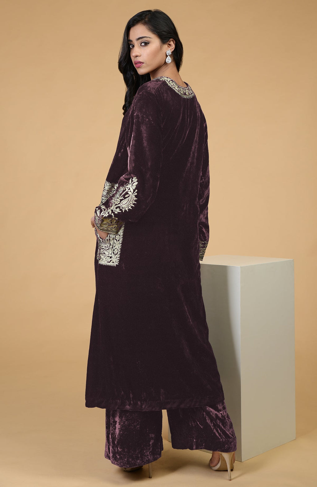 A woman models a mulled wine velvet kurta set with Kashmiri tilla embroidery.