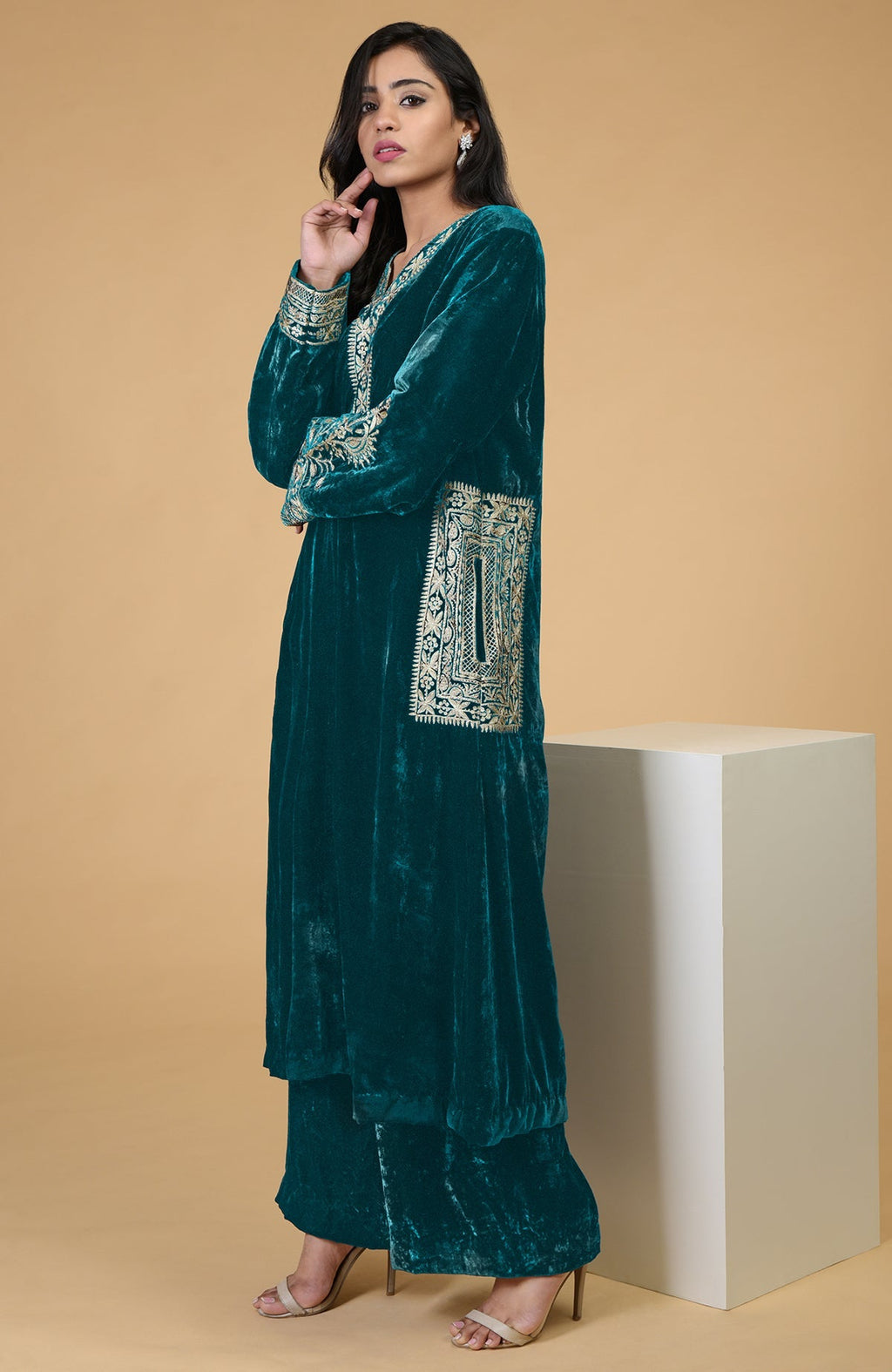 A woman models a teal velvet kurta set with Kashmiri tilla embroidery.