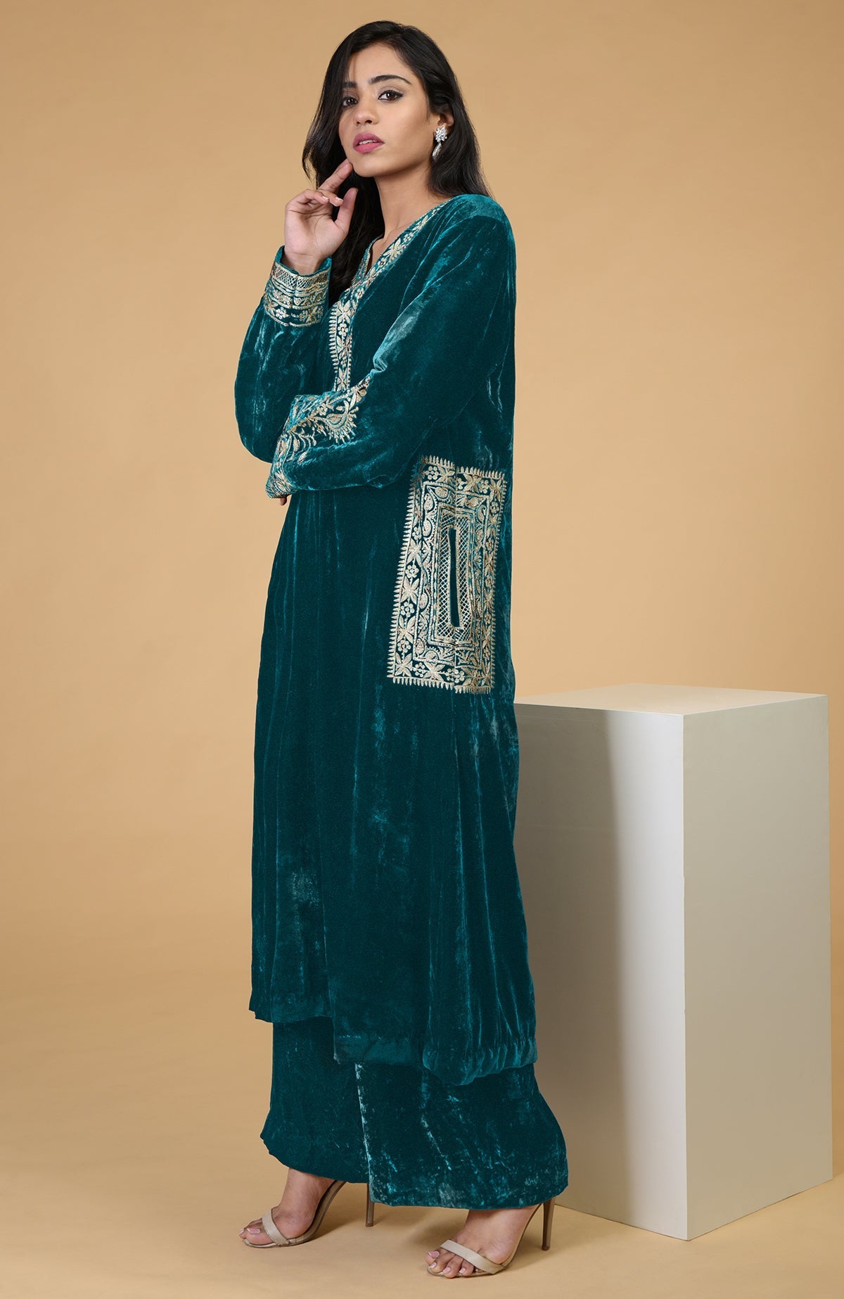 A woman models a teal velvet kurta set with Kashmiri tilla embroidery.