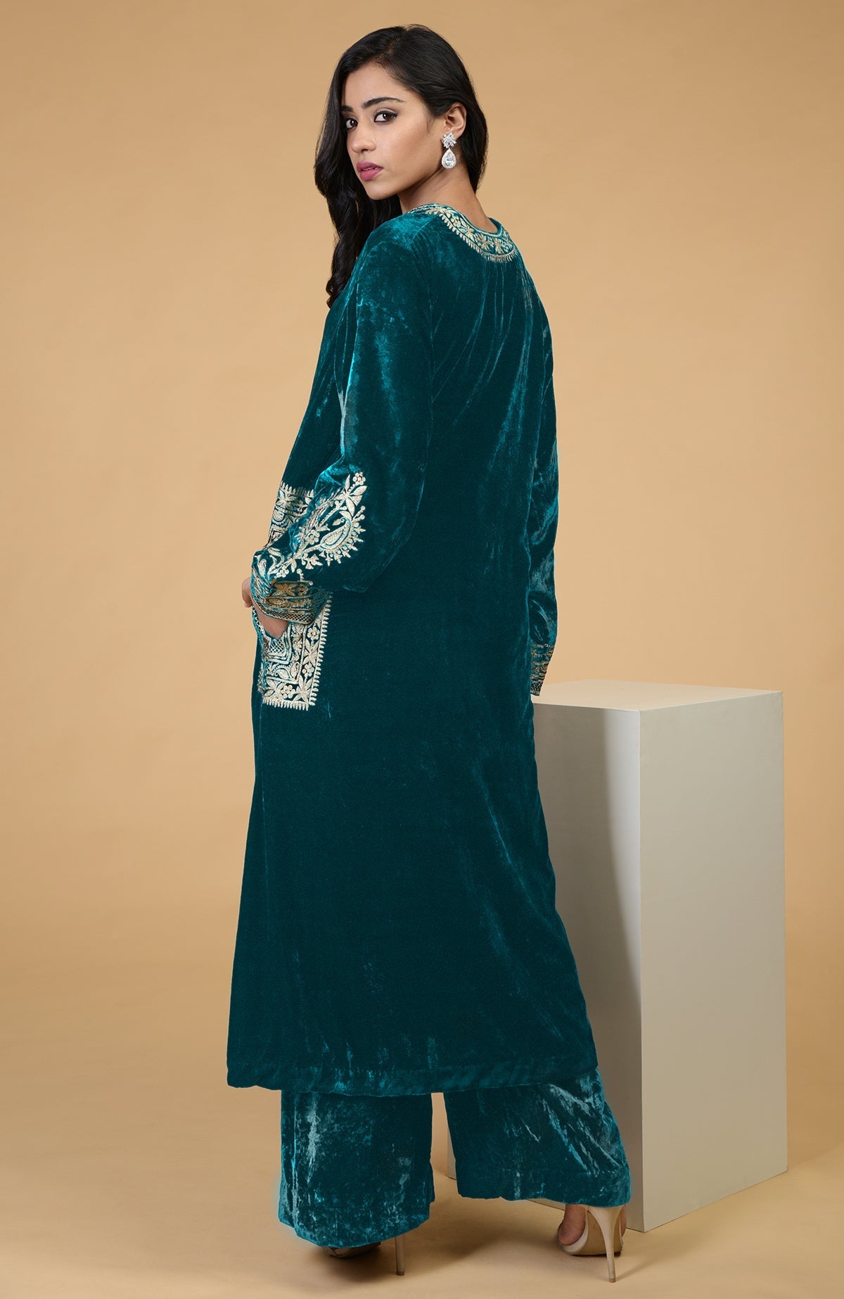 Teal velvet kurta set with Kashmiri tilla embroidery on the neckline, pockets, and sleeves.