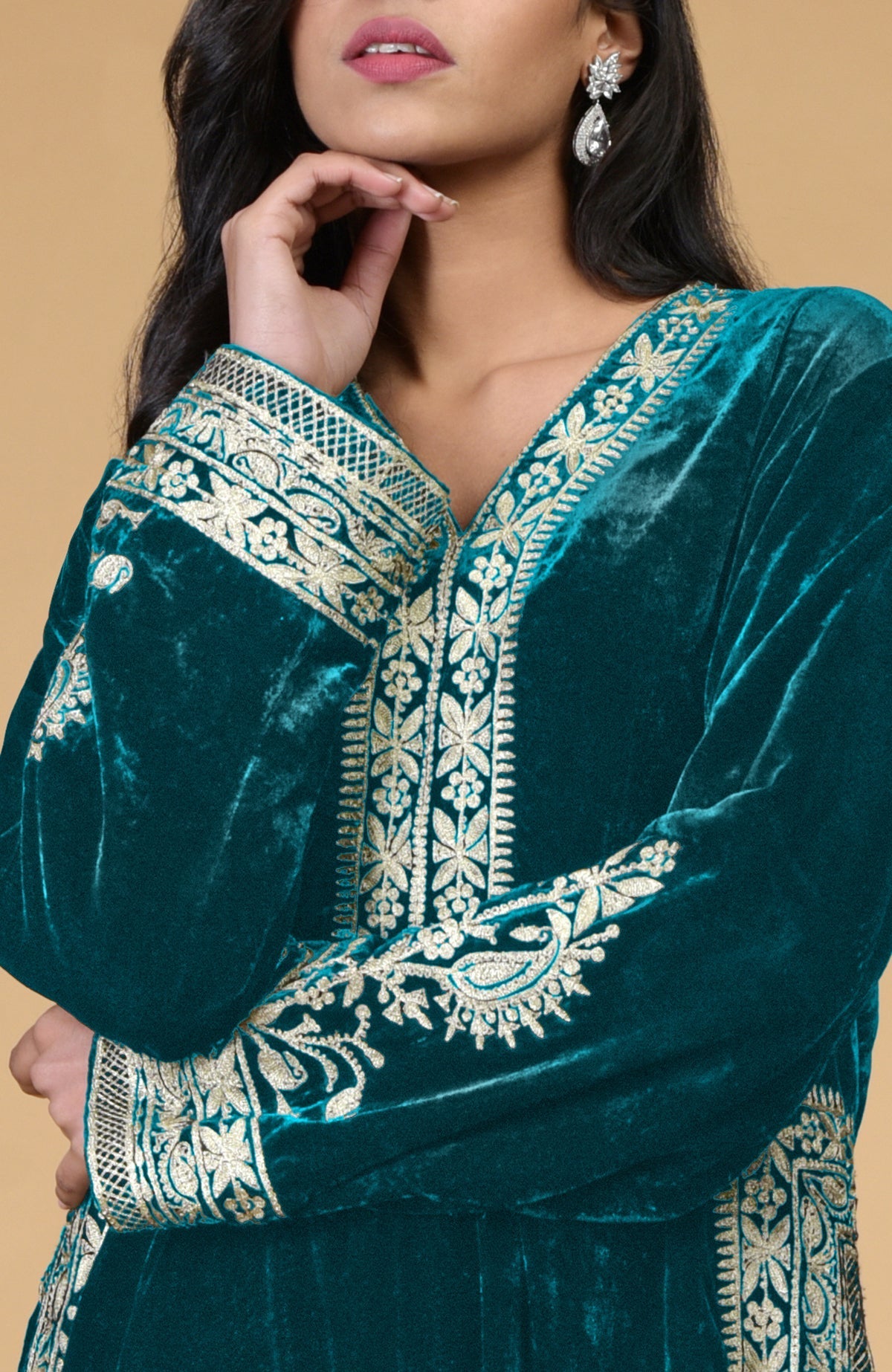 A woman models a teal velvet kurta with intricate silver tilla embroidery.