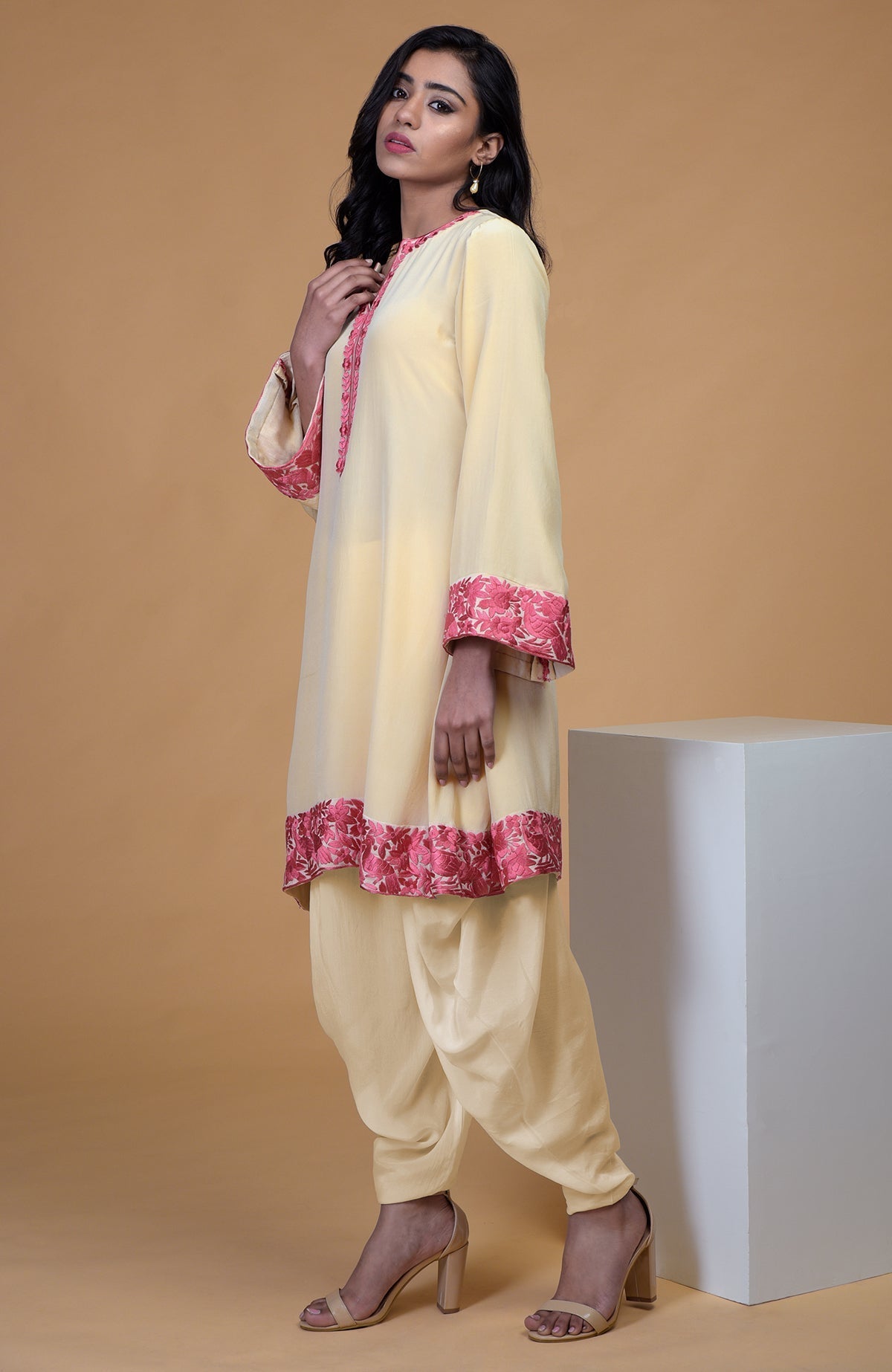 Beige short kurta with rose wine floral parsi gara embroidery on hem, neckline, and sleeves paired with beige dhoti pants