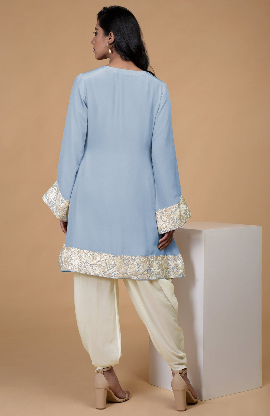 A woman models a dusty blue Parsi Gara embroidered Patiala pants suit from the back.