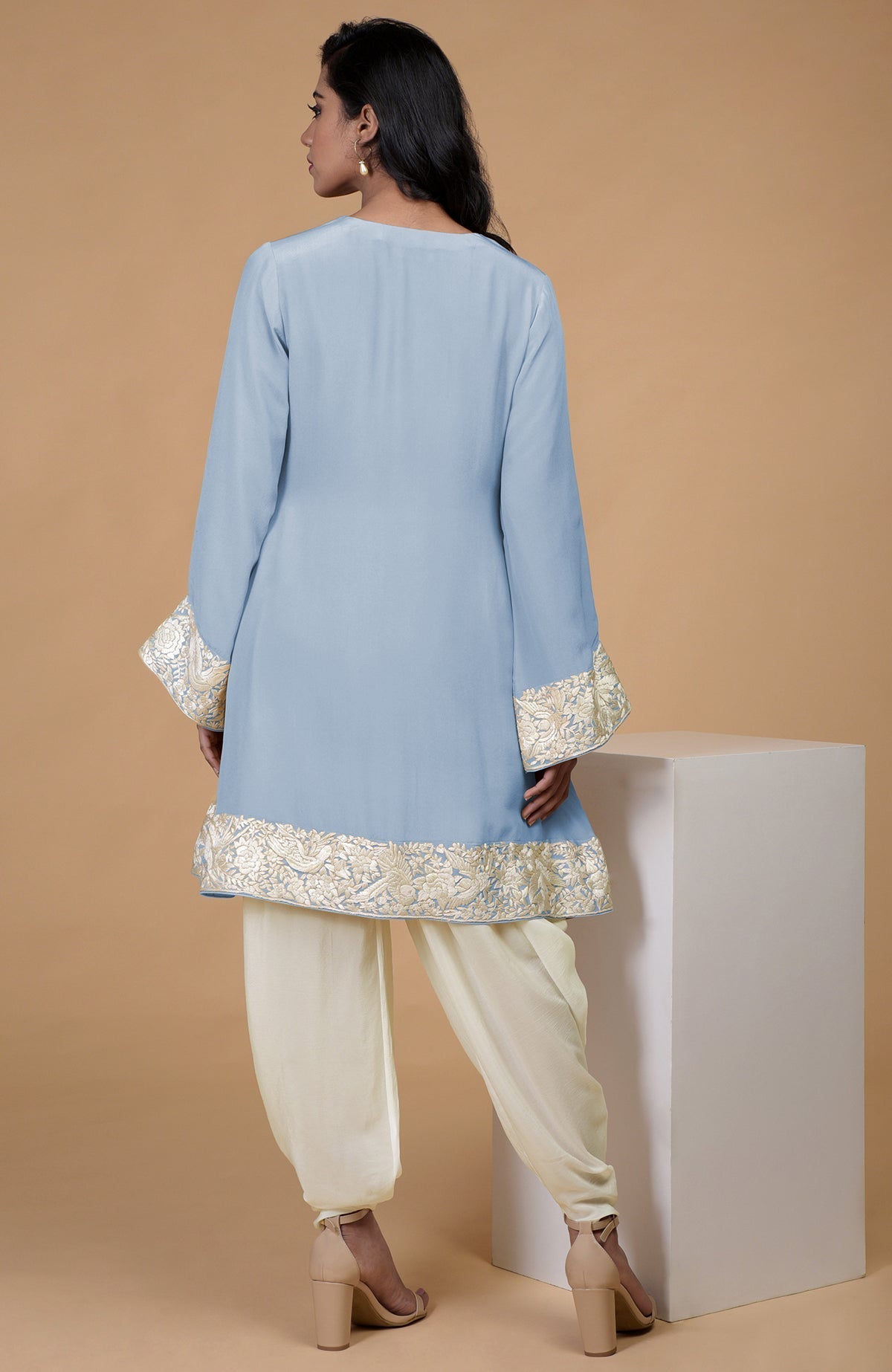 A woman models a dusty blue Parsi Gara embroidered Patiala pants suit from the back.