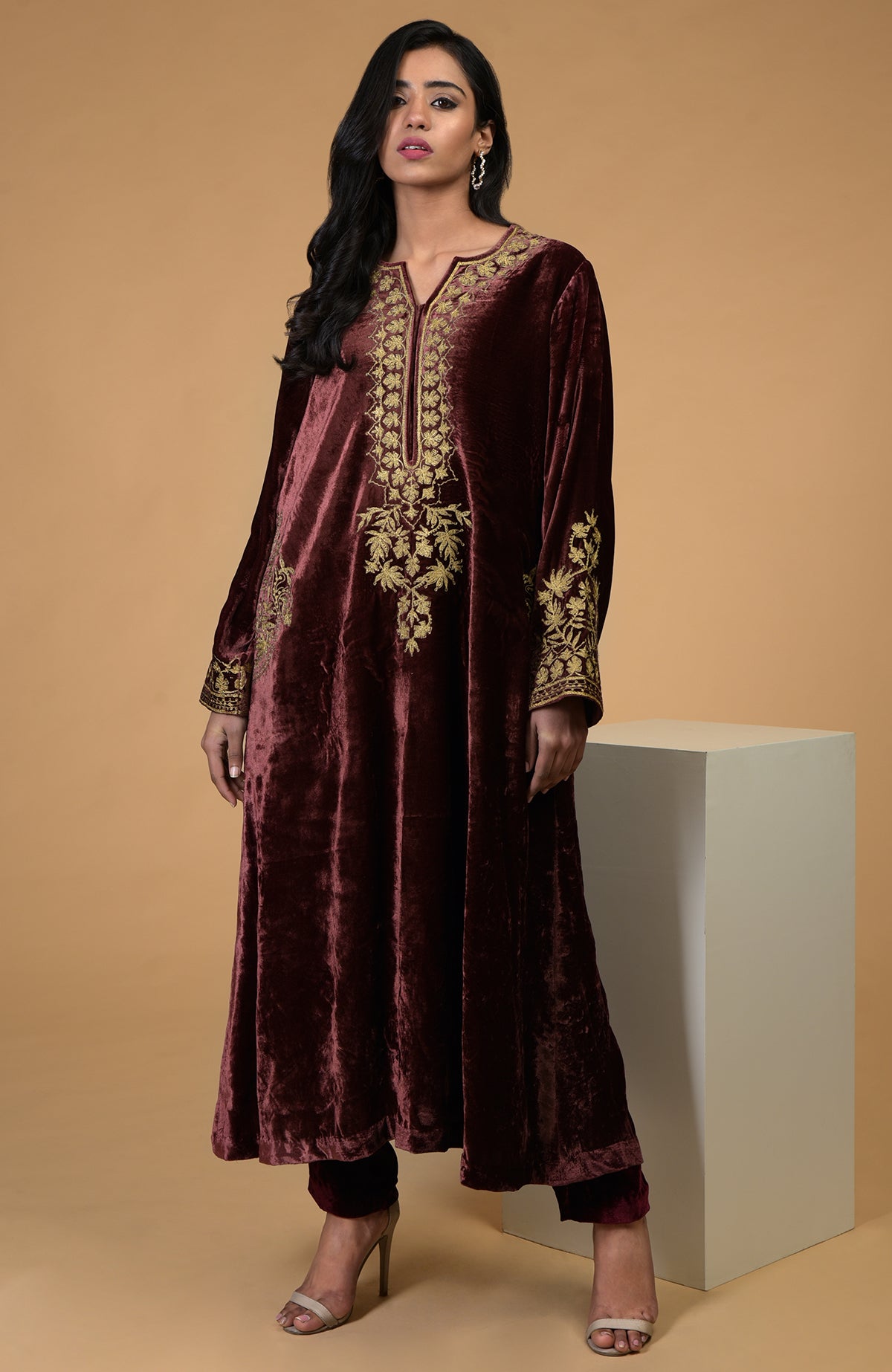 A woman models a rusty rose velvet kurta set with gold Kashmiri tilla aari embroidery.