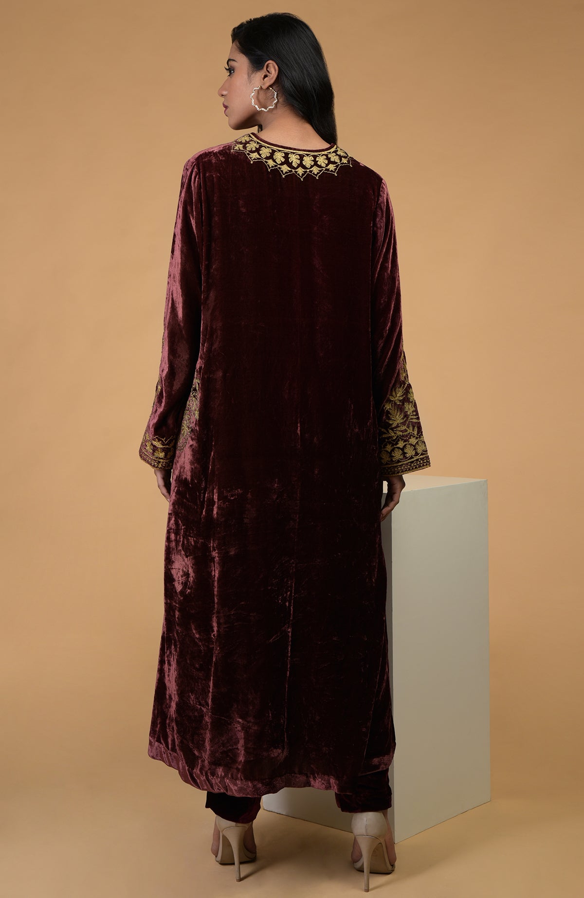A woman models a rusty rose velvet kurta set with gold embroidery.