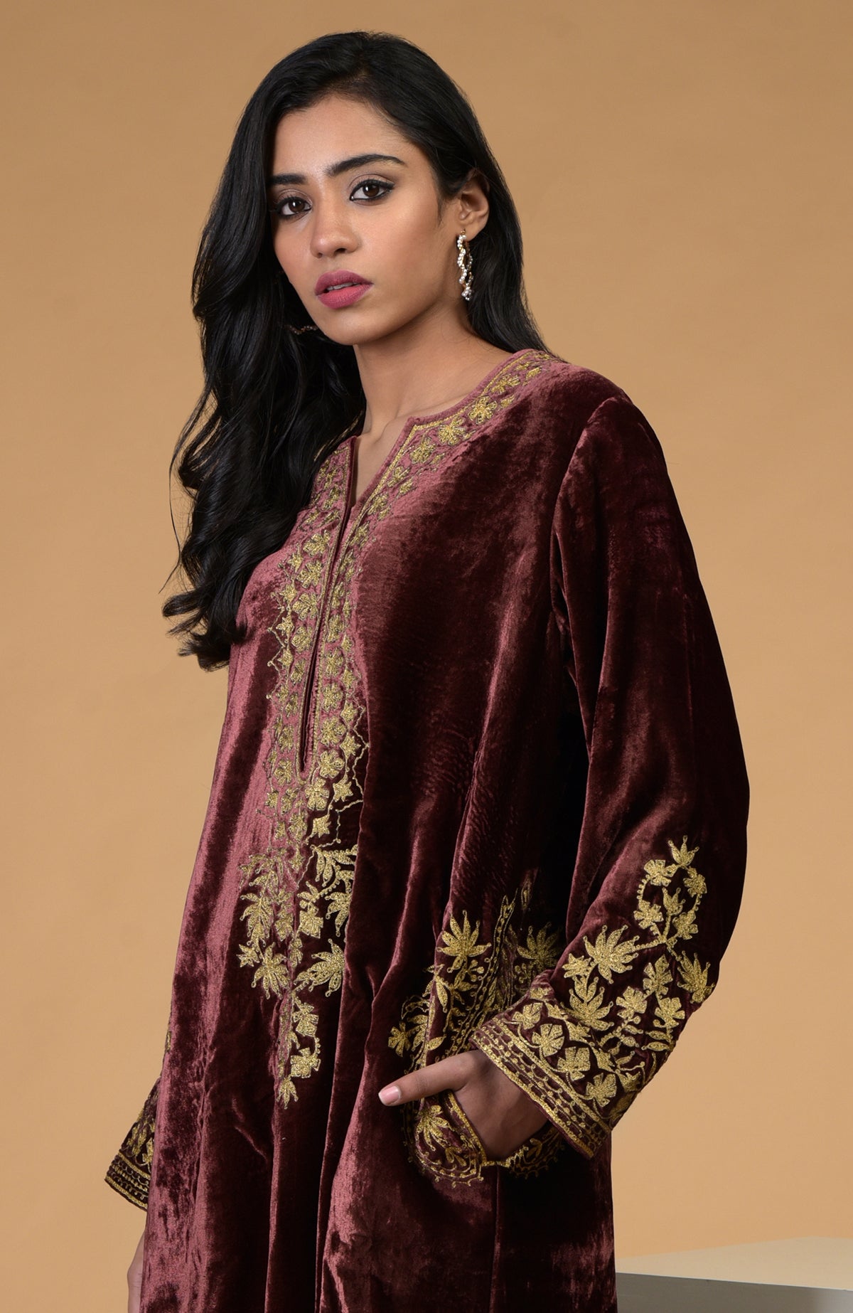 A woman models a rusty rose velvet kurta with gold Kashmiri tilla aari embroidery.