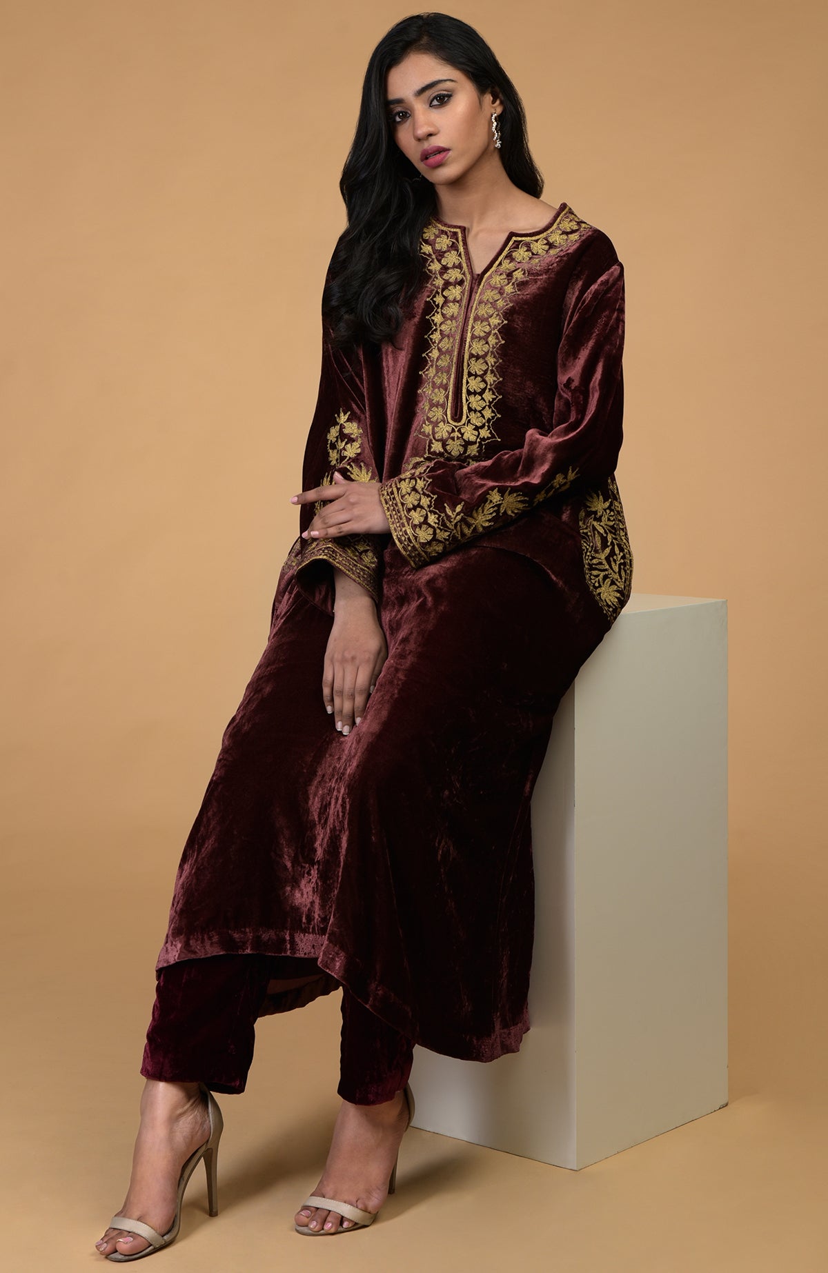 A woman models a rusty rose velvet kurta set with gold Kashmiri tilla aari embroidery.