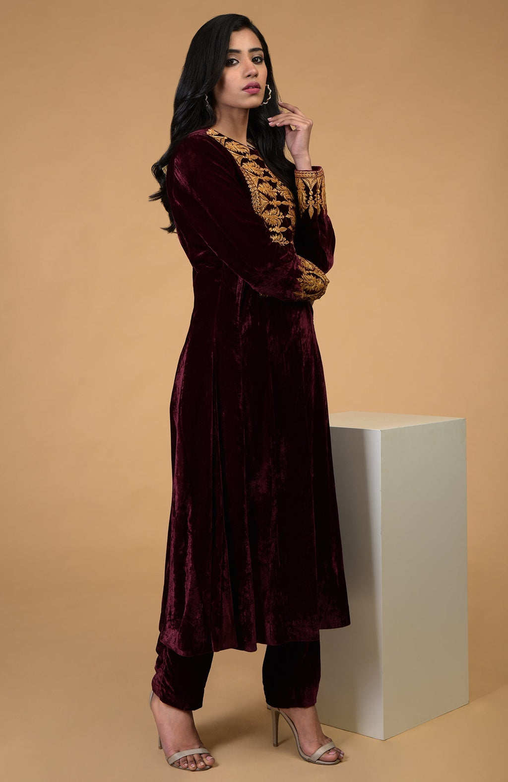A woman models a rose maroon gold Kashmiri tilla embroidered kurta set.