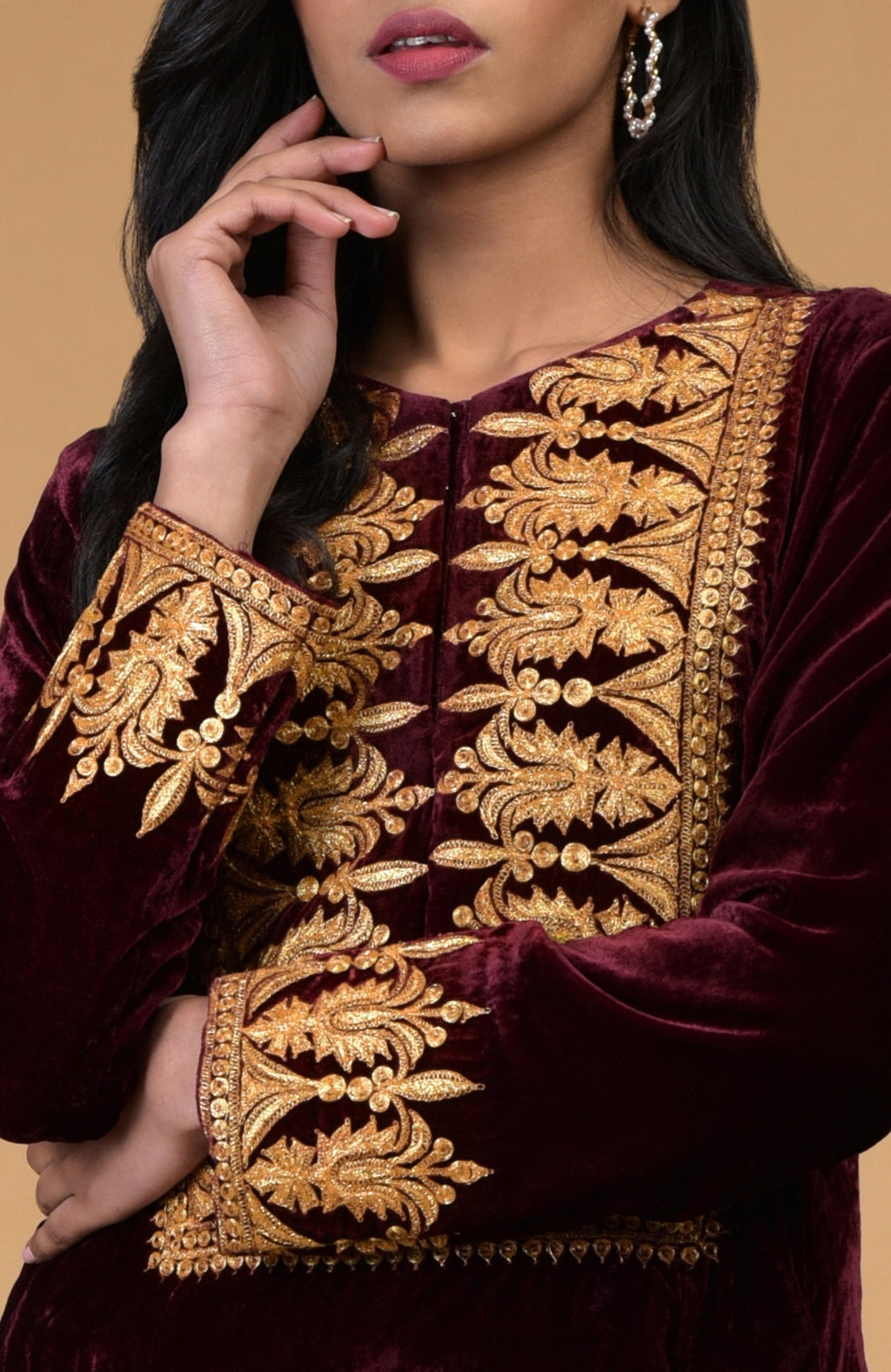 A woman models a rose maroon velvet kurta with gold Kashmiri tilla embroidery.